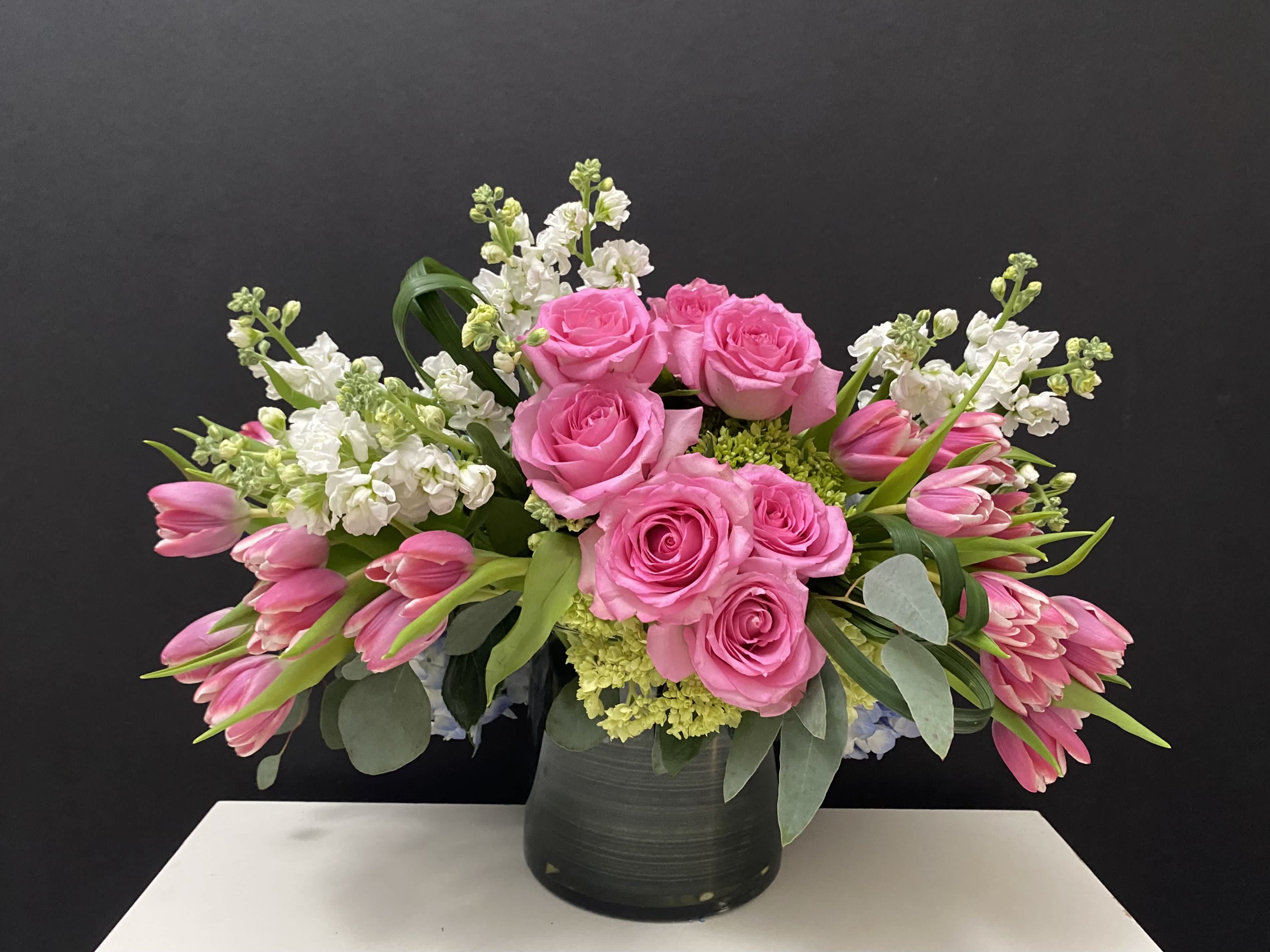 Pink roses and tulips arranged in a black vase
