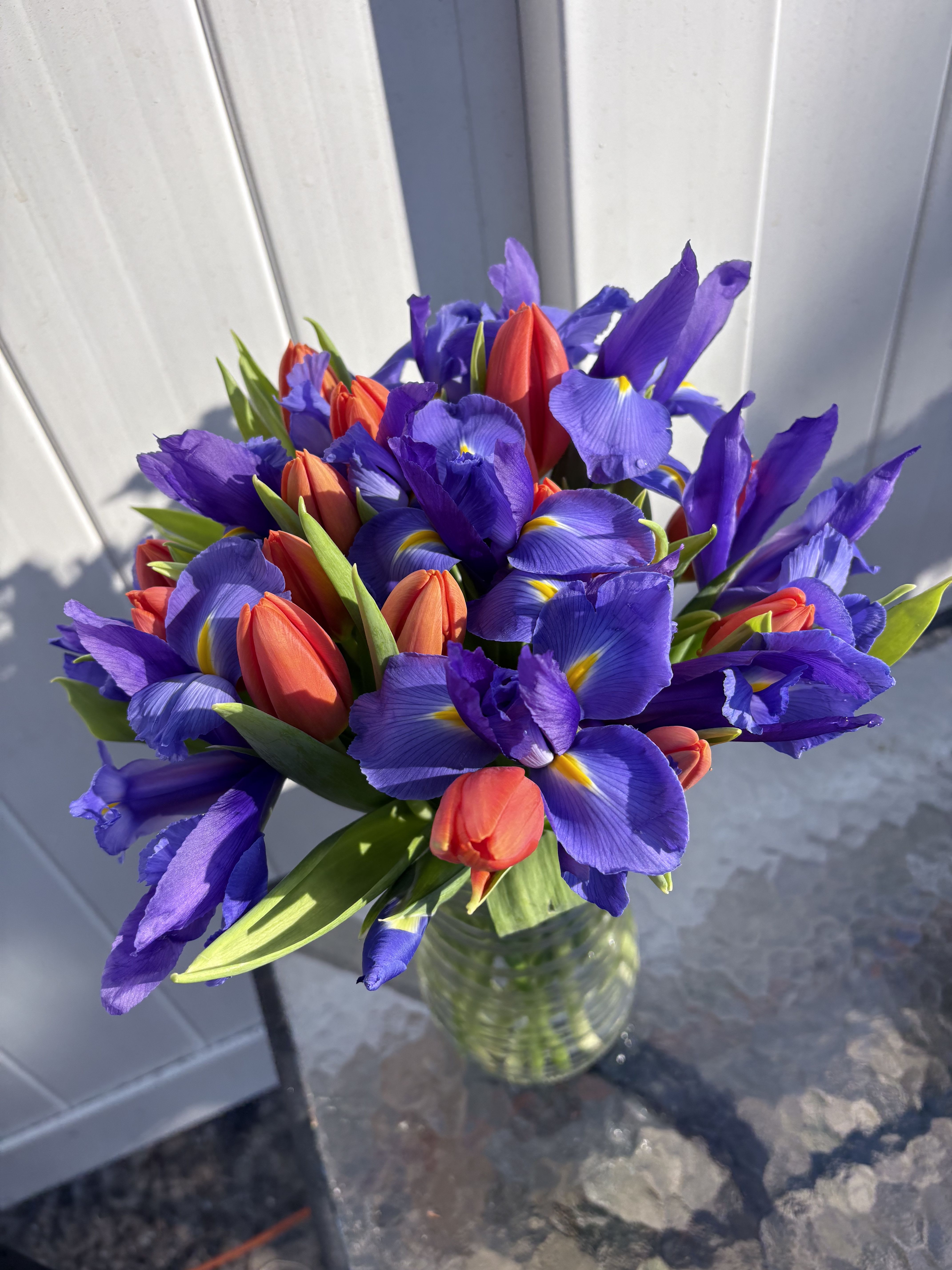 Bouquet of purple irises and red tulips in a glass vase