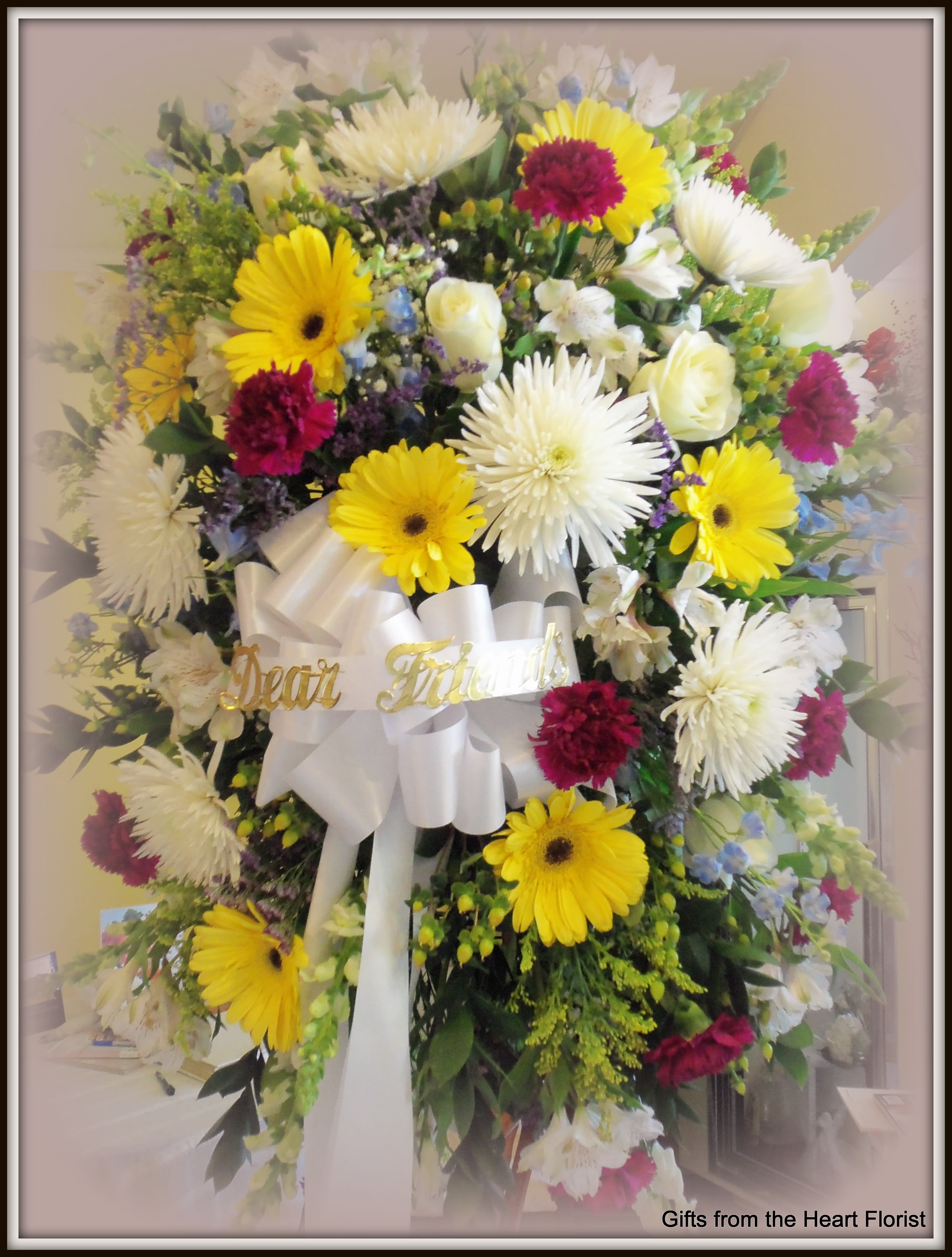 Large mixed flower standing spray with white ribbon and gold lettering
