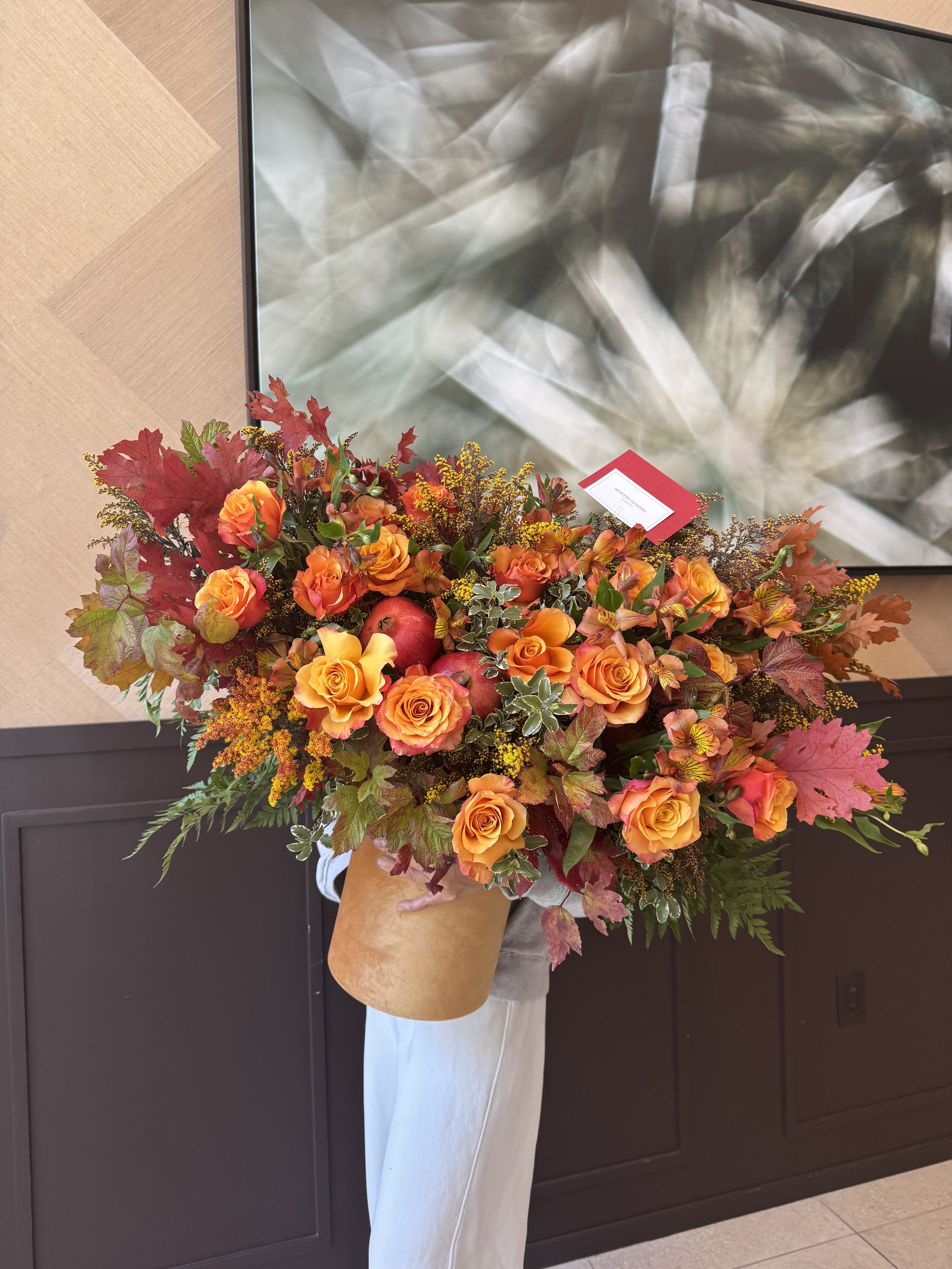 Large bouquet of orange roses with autumn leaves and red apples