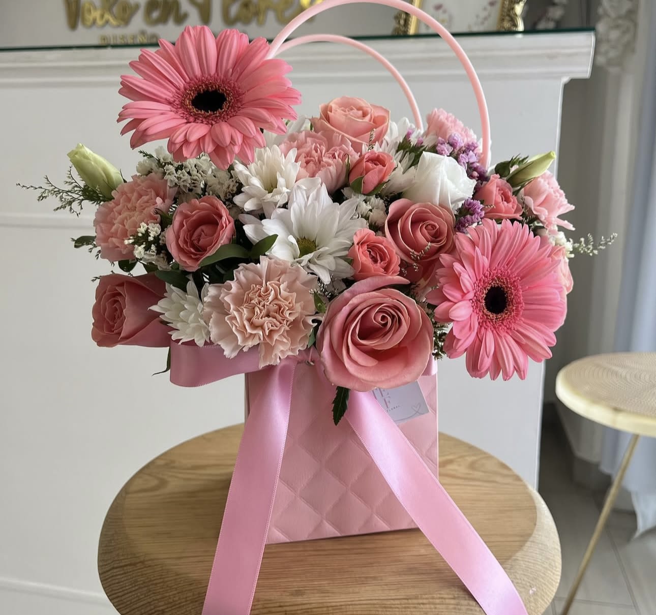 Pink and white flower arrangement in a pink gift bag with ribbon handles