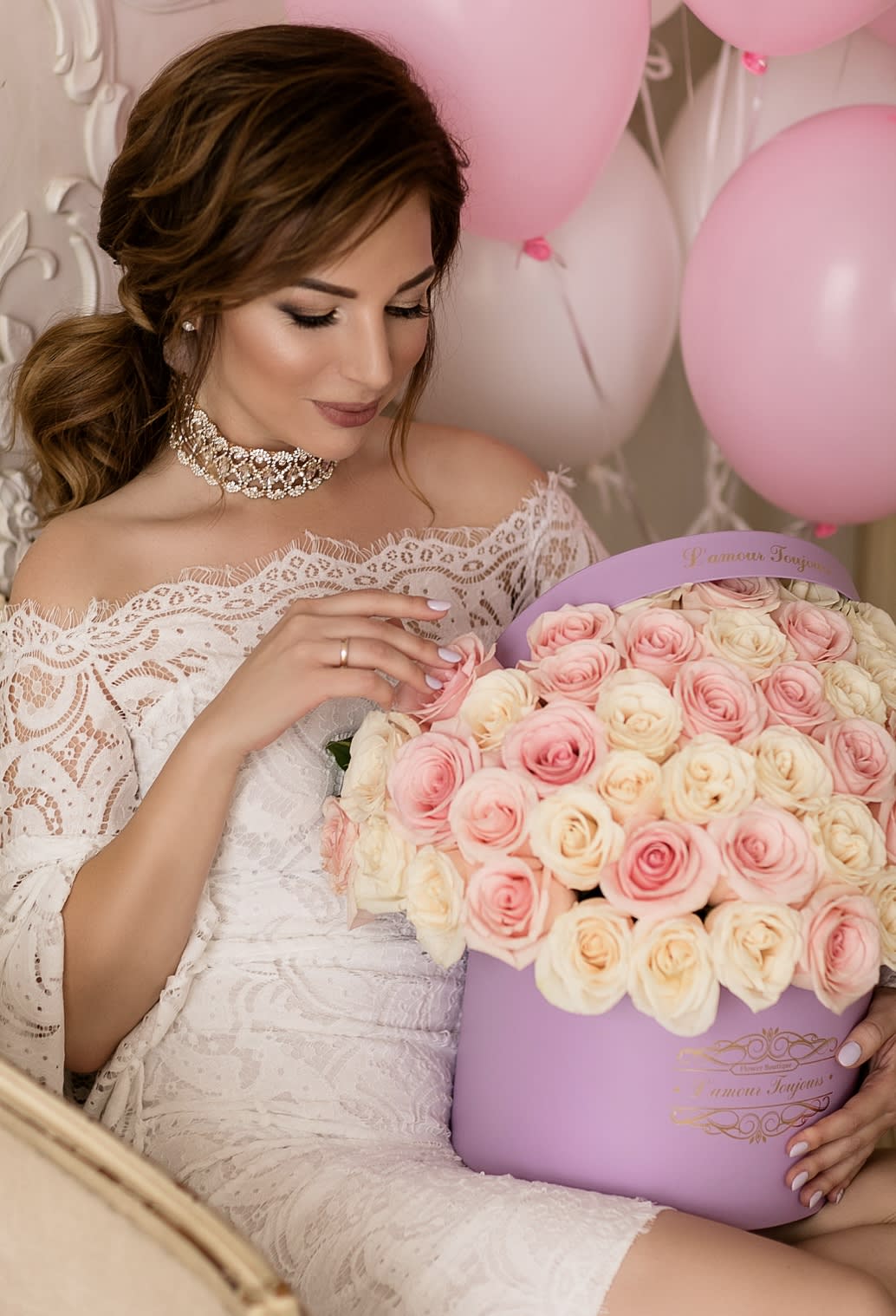Woman in lace dress holding a lavender hat box filled with pink and cream roses