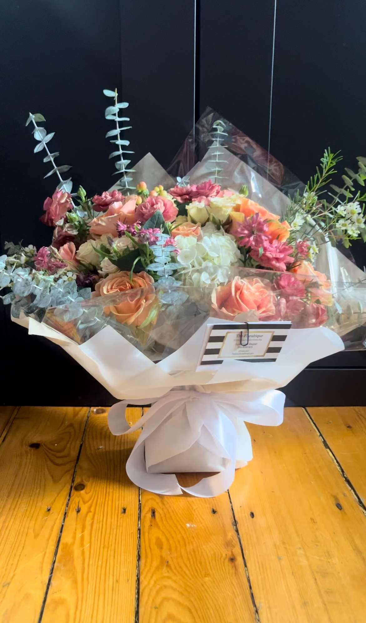 Bouquet of peach and pink roses with white hydrangea in clear wrap