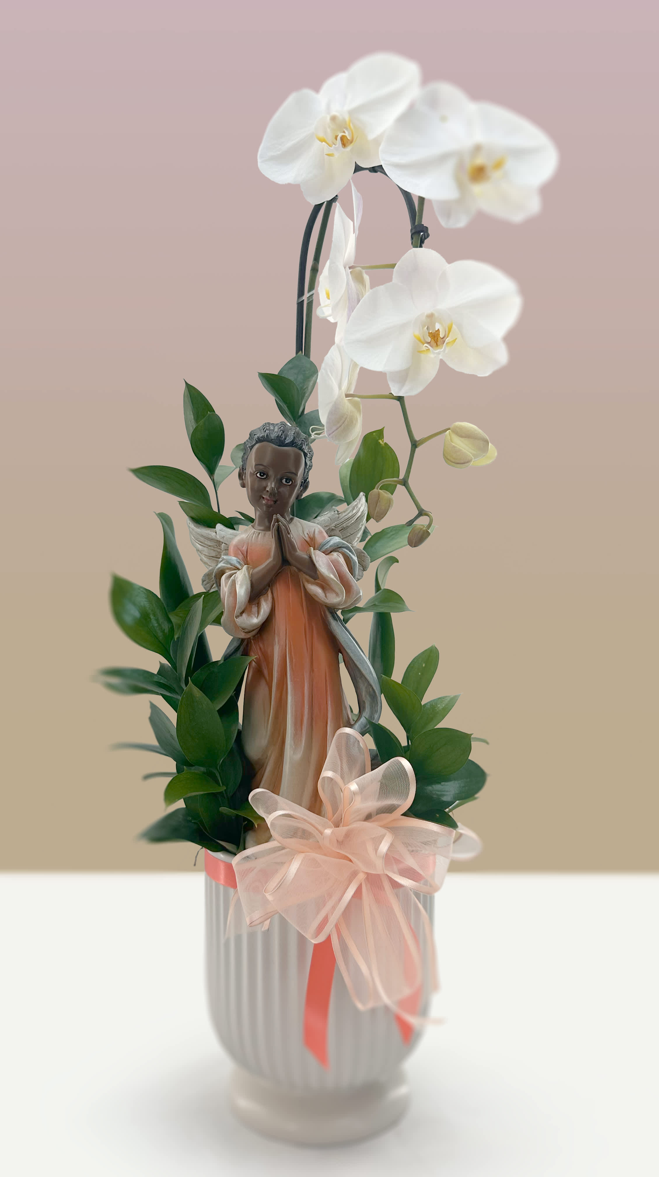 Healing Prayer - Bring comfort, grace, and a sense of profound peace to those you care about with the Healing Prayer arrangement. This exquisite tribute combines the timeless elegance of a premium orchid plant with the fresh, vibrant textures of Italian ruscus, creating a living sanctuary of quiet beauty and reflection.  Perfect for expressing heartfelt sympathy, sending healing thoughts, or offering a serene token of remembrance, this arrangement serves as an enduring reminder of love, support, and hope during life's most tender moments.  *Please specify which angel you would like to adorn the plant.  