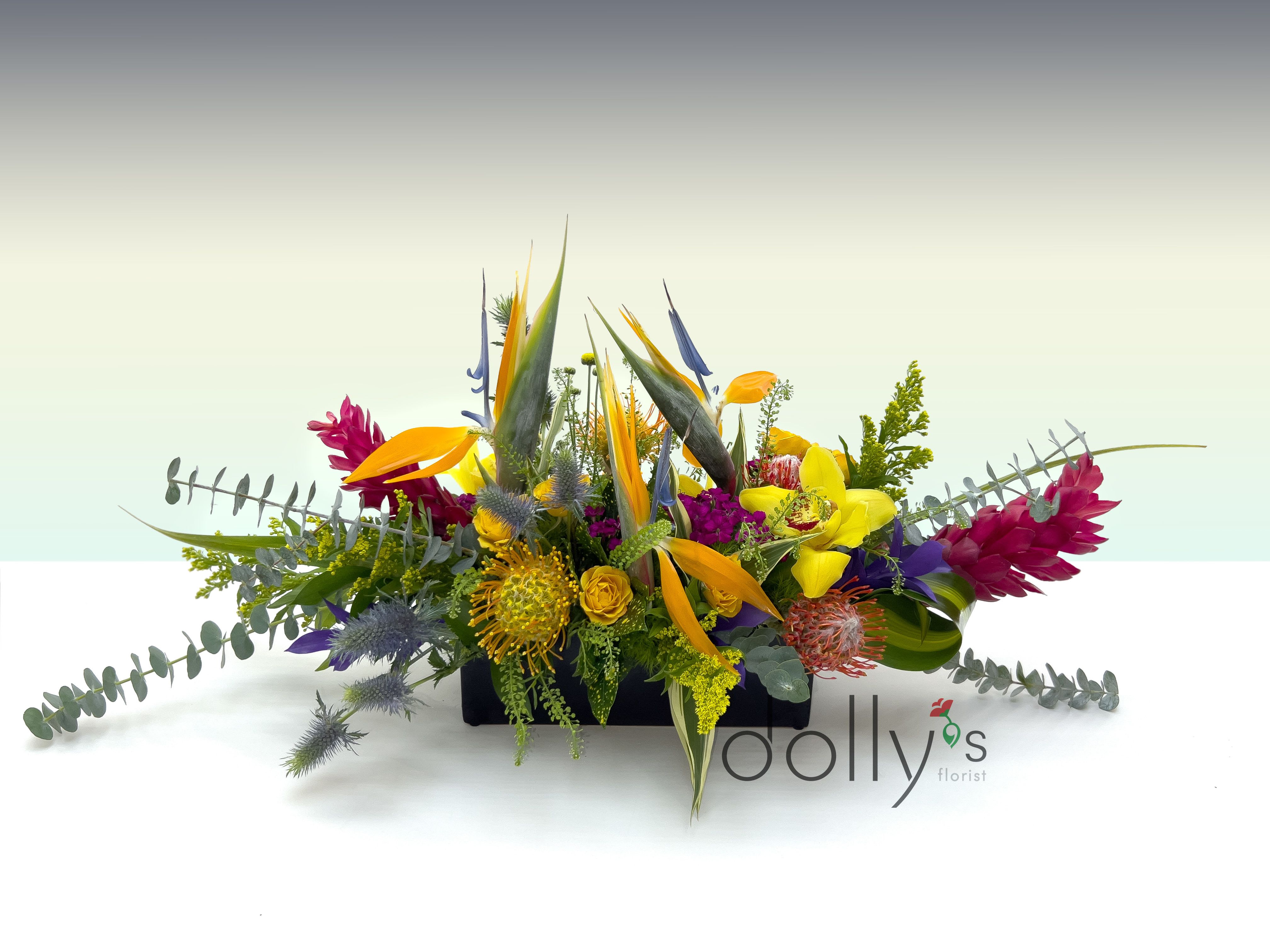Colorful tropical flower arrangement in a low rectangular container