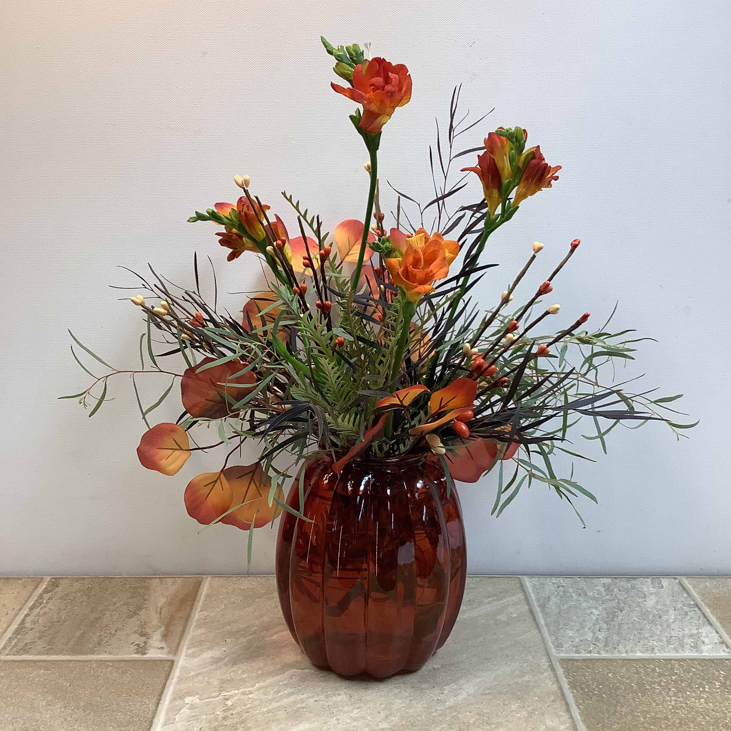 Orange floral arrangement in a brown glass vase