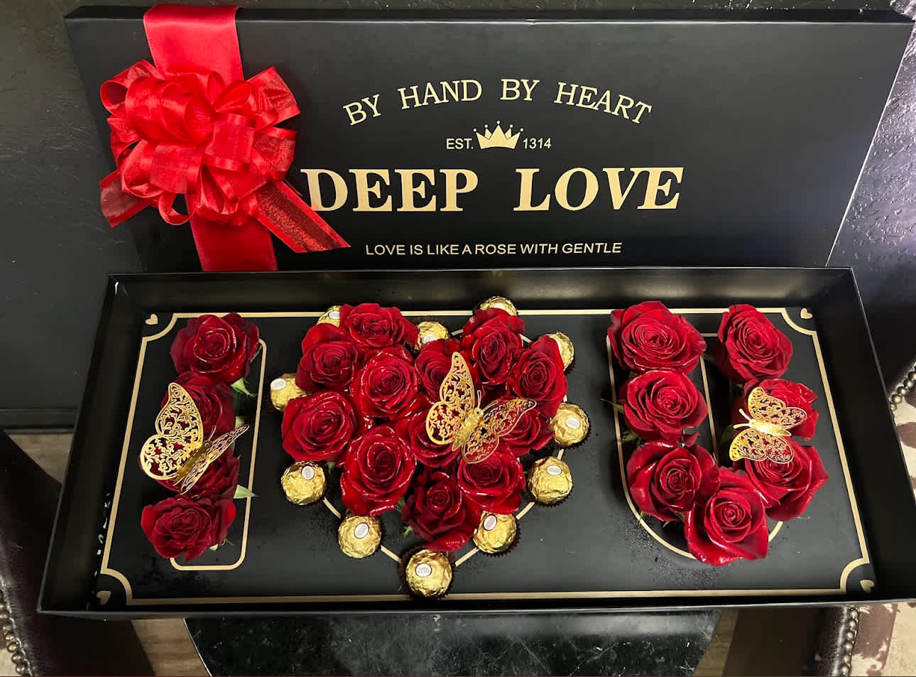 Red roses and gold-wrapped chocolates arranged in a gift box
