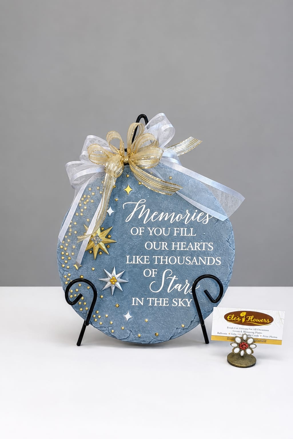 Blue memorial plaque with gold ribbon and star accents on a stand