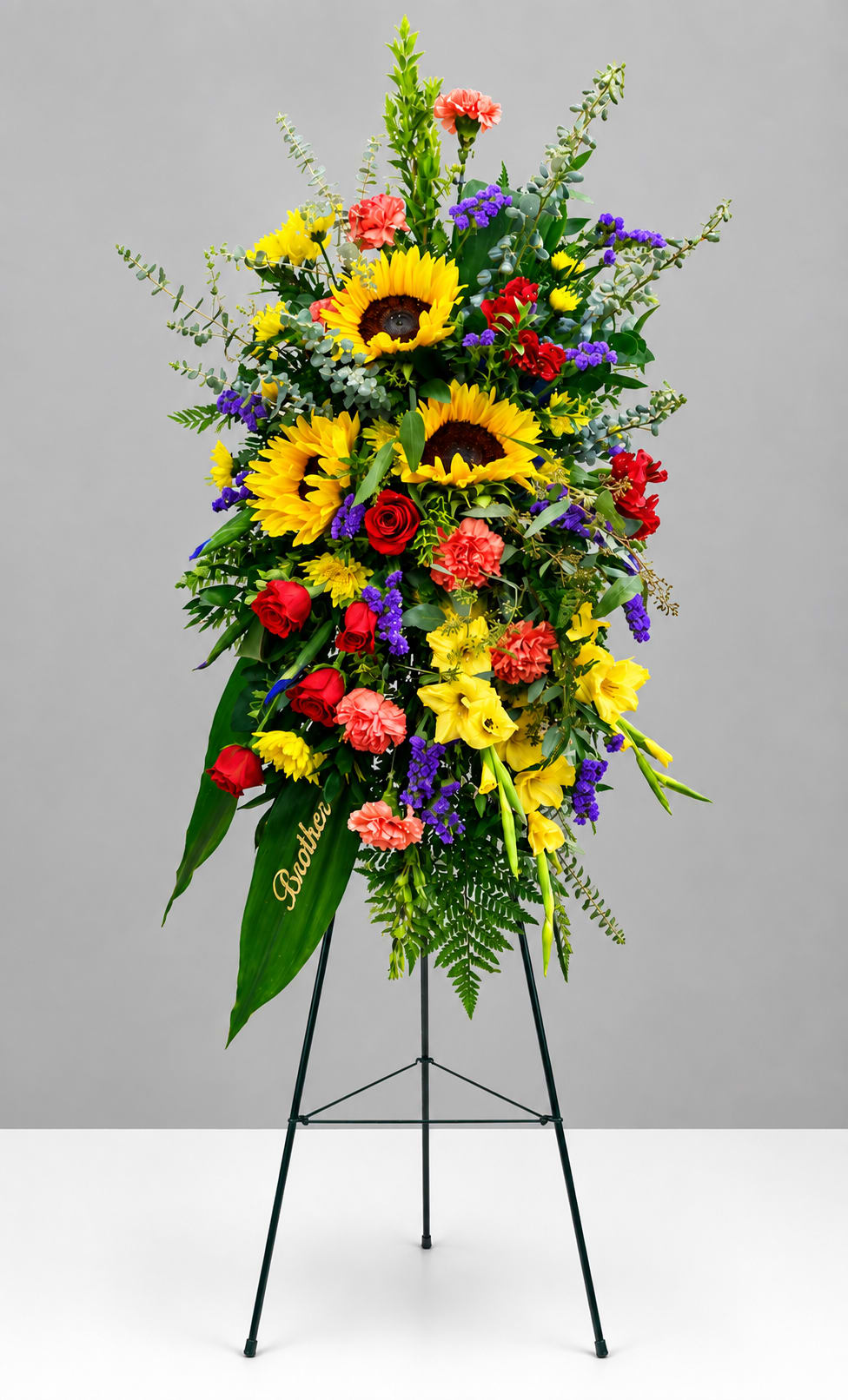 Tall standing floral spray with sunflowers, roses, and carnations on an easel