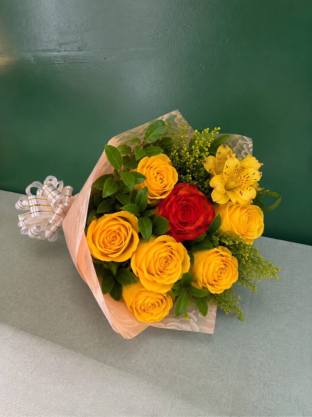Bouquet of yellow and red roses with yellow alstroemeria in pink wrap