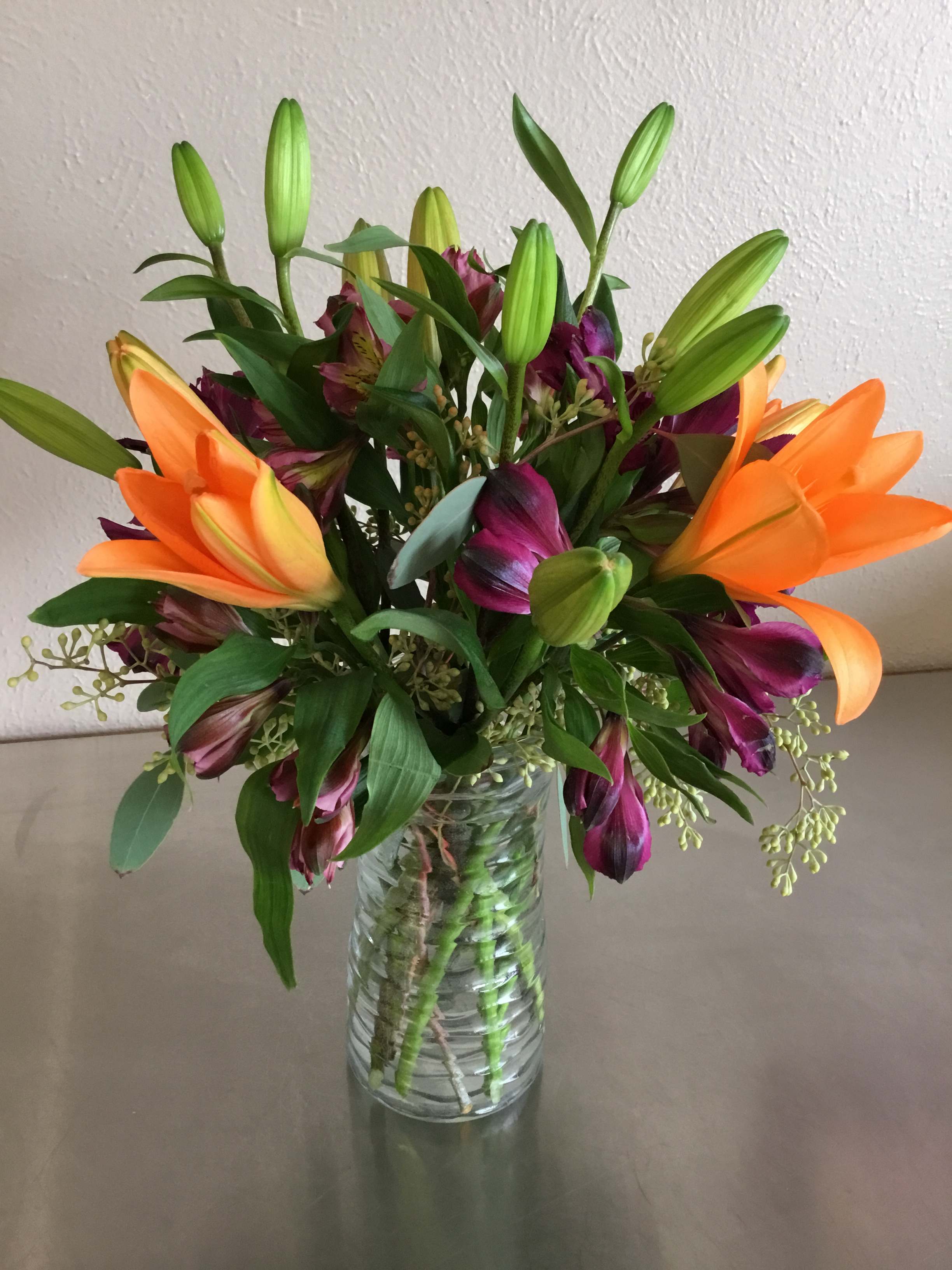 Cleo - Brightly colored Asiatic lily (color may vary), complementary colored alstroemeria, and greenery make this the epitome of happiness.  Note: Lilies are toxic to cats.