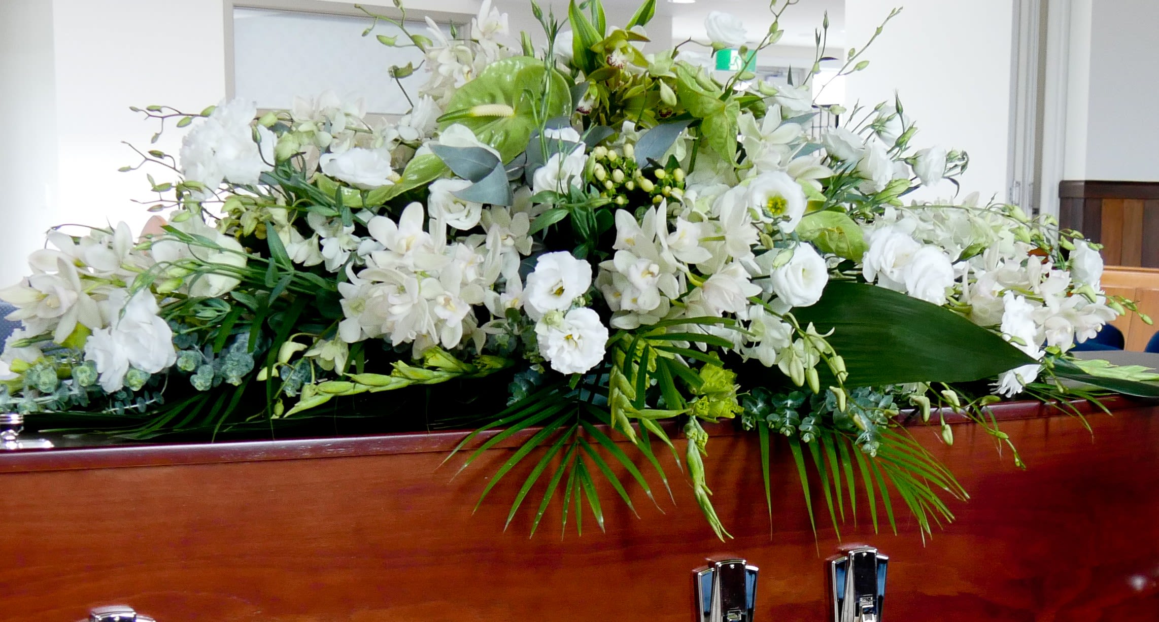 Large white floral spray arranged on a wooden casket