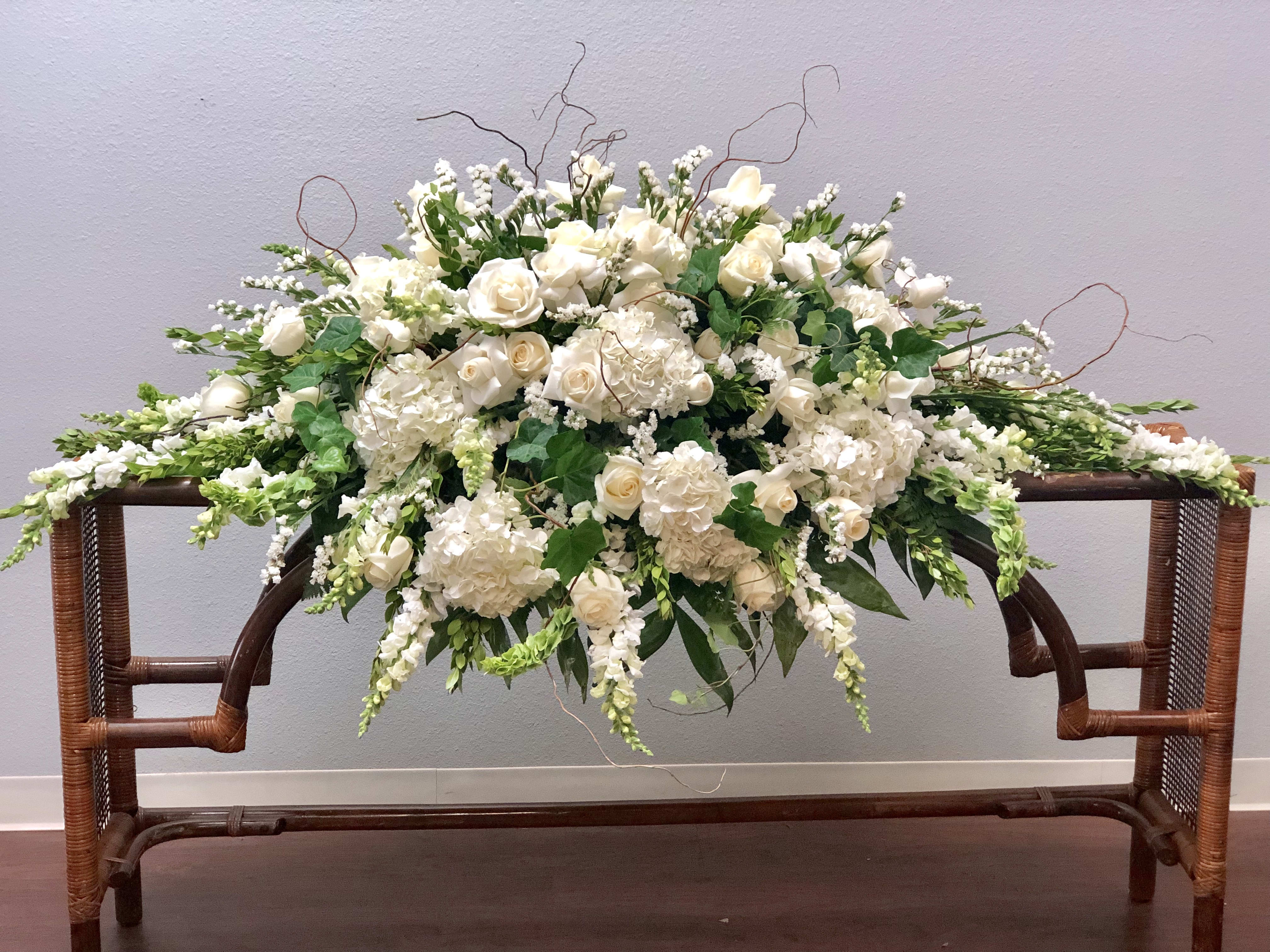 Large white floral arrangement with roses and hydrangeas on a wooden table