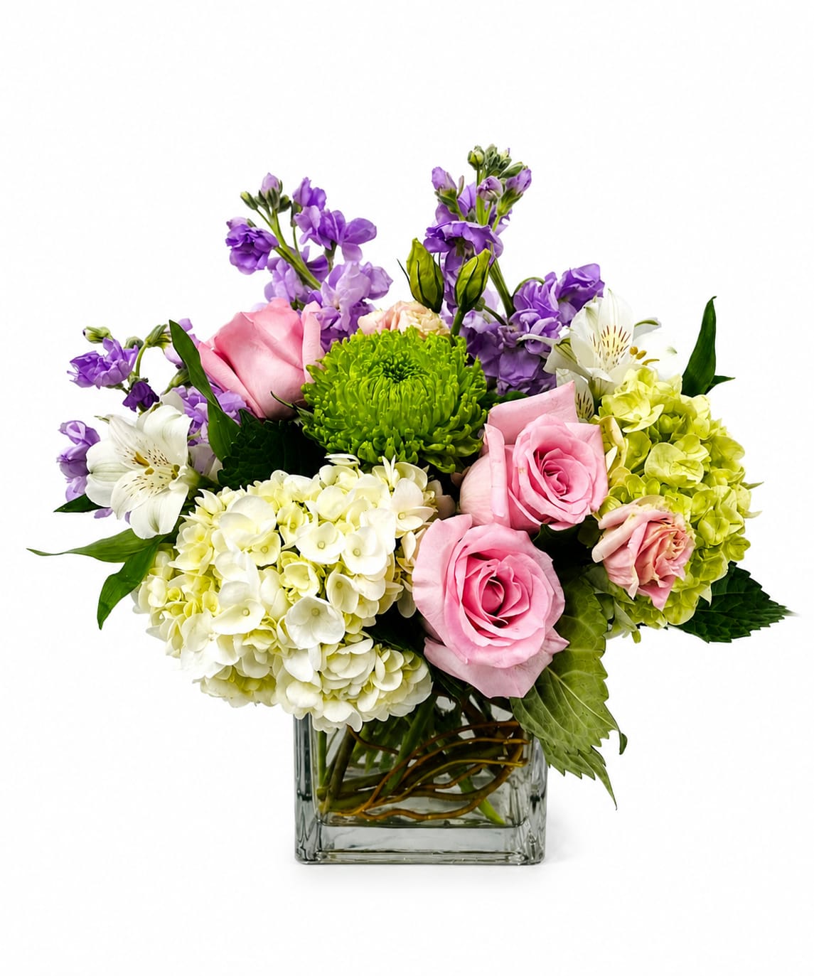 Belle - A charming arrangement of blush pink roses, white and green hydrangeas, lavender stock, white alstroemeria, and a vibrant green spider chrysanthemum. Designed in a modern glass cube vase, this fresh floral centerpiece brings elegance and a touch of spring to any occasion.