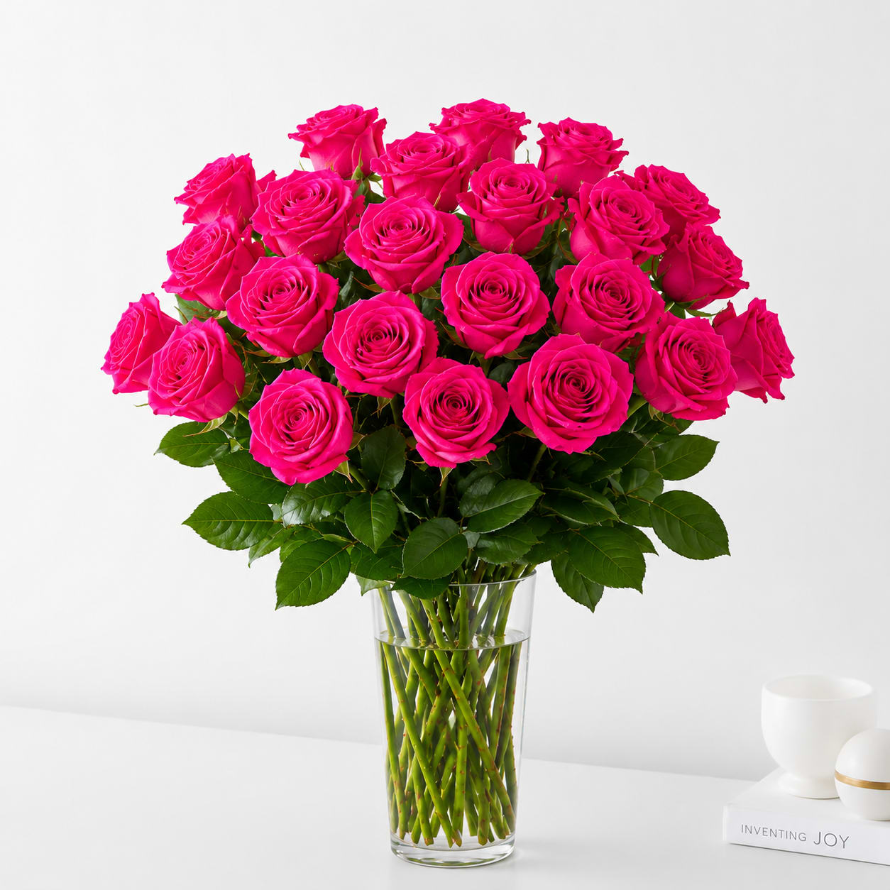 Two Dozen Hot Pink Roses  - Elegant, and timeless, this bouquet of premium hot pink roses is beautifully arranged in a clear glass vase with lush greenery. A graceful expression of admiration, gratitude, and affection, it's the perfect gift for birthdays, anniversaries, congratulations, or simply to brighten someone's day.
