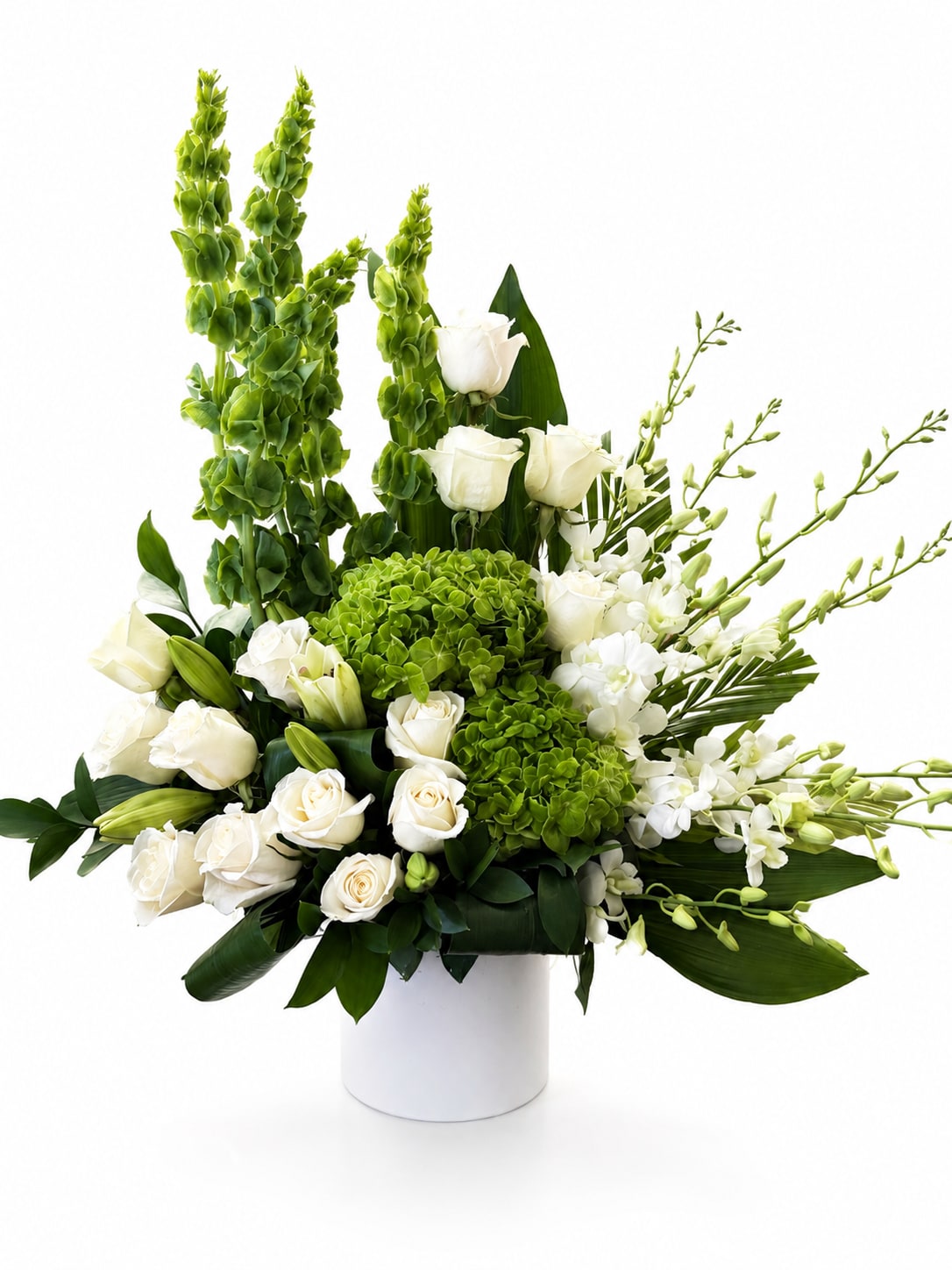 White roses and green blooms arranged in a white vase