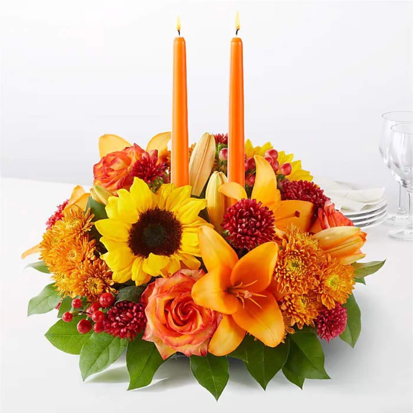 Orange floral centerpiece with two orange candles
