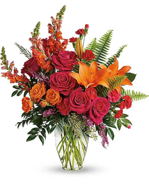 Bright mixed bouquet of roses and lilies in a clear glass vase