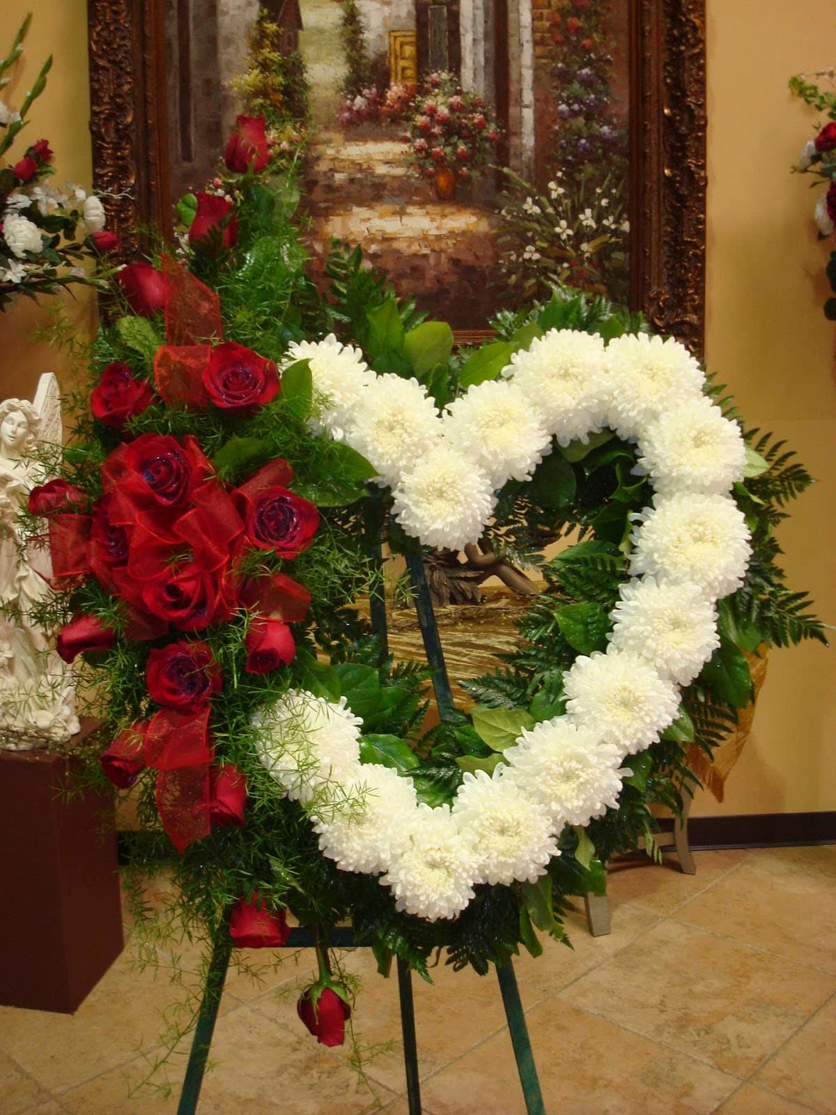 Heart-shaped floral wreath with white and red flowers on an easel