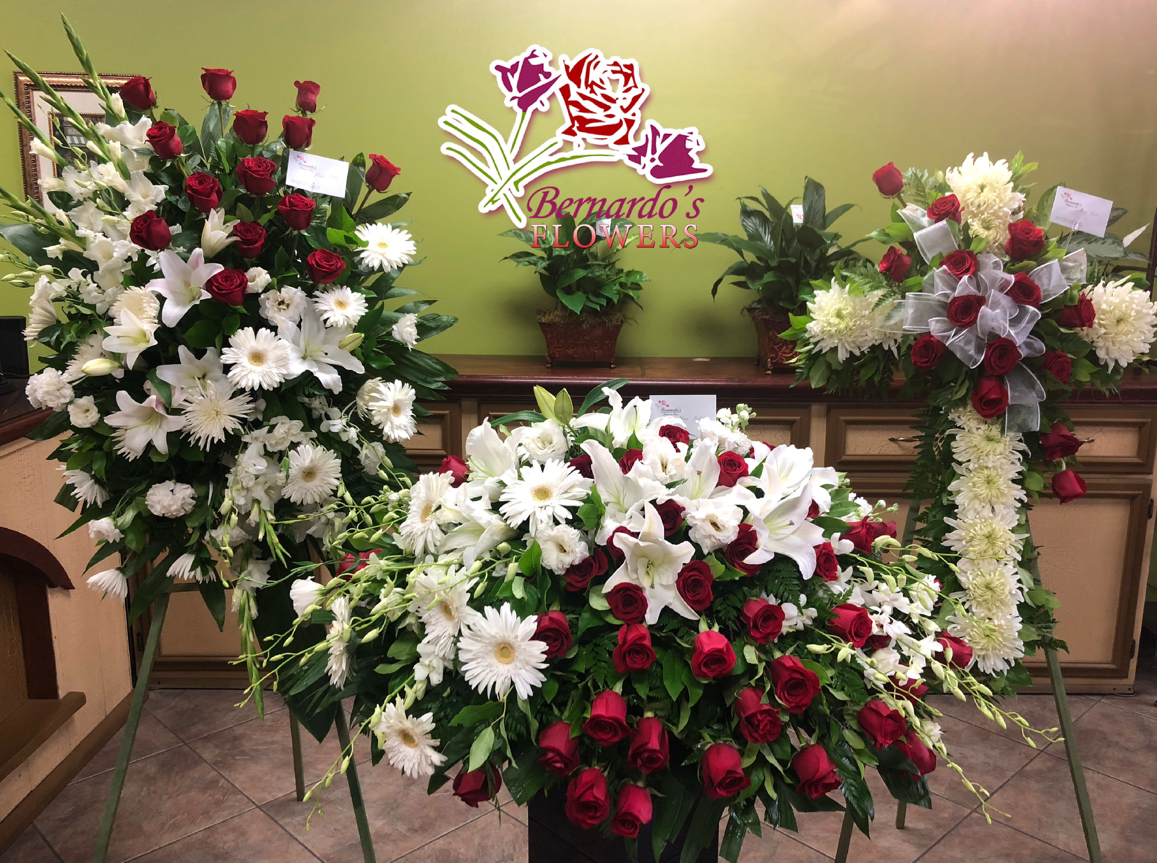 Large funeral floral sprays with red roses and white lilies and daisies