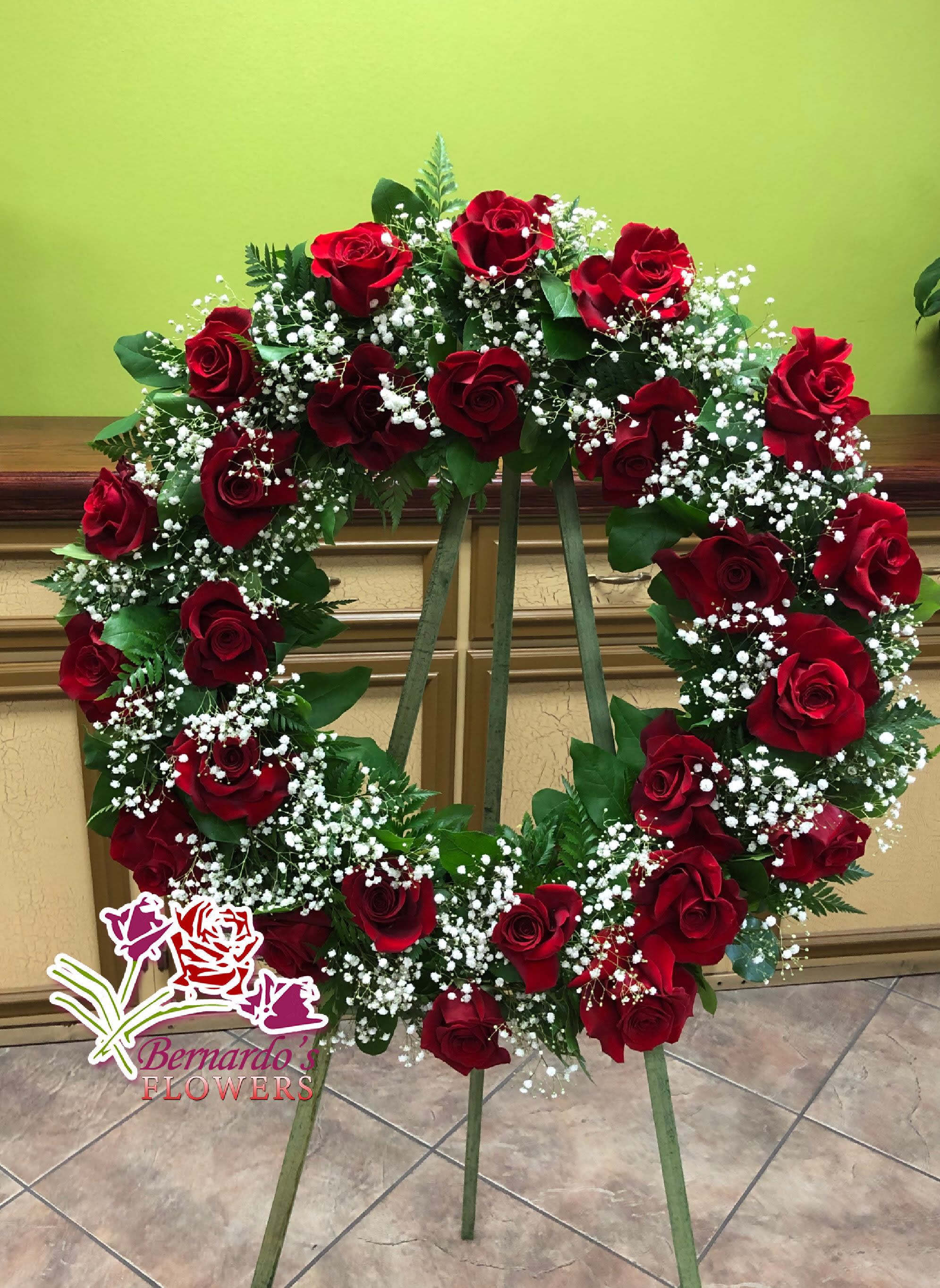 Heart-shaped wreath of red roses and white baby's breath on an easel