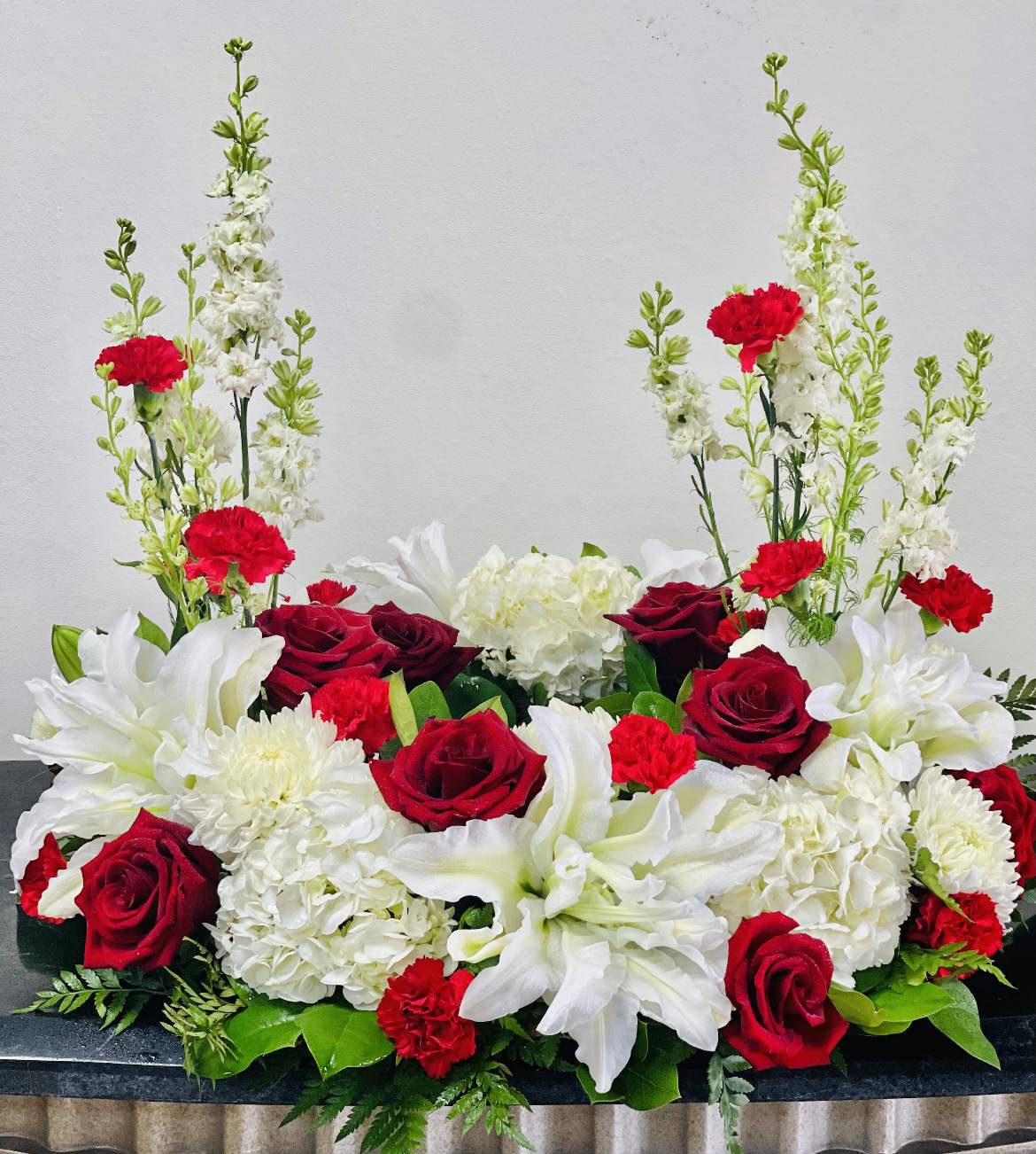 Red roses and white lilies arranged with white hydrangeas and carnations
