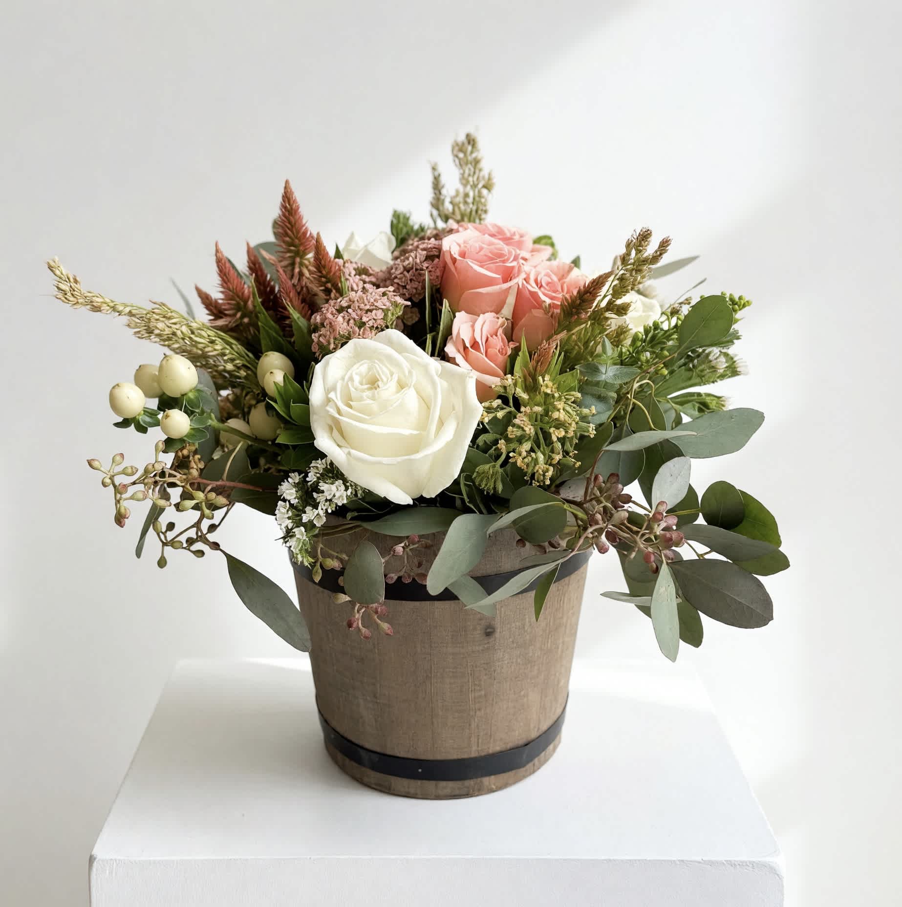 Bouquet of pink and white roses in a rustic round container