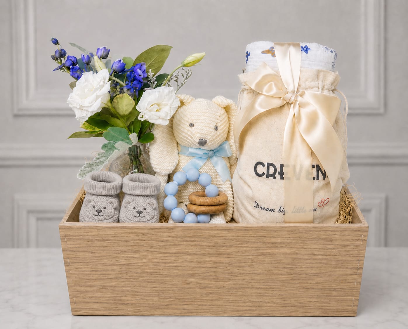 Gift basket with white and blue flowers, baby socks, a teddy bear, and baby items