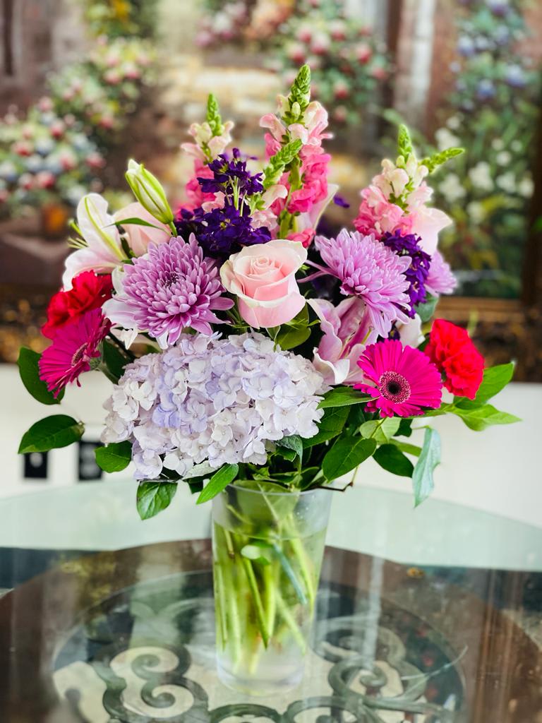 Mixed bouquet in a clear glass vase with pink, purple, and white flowers