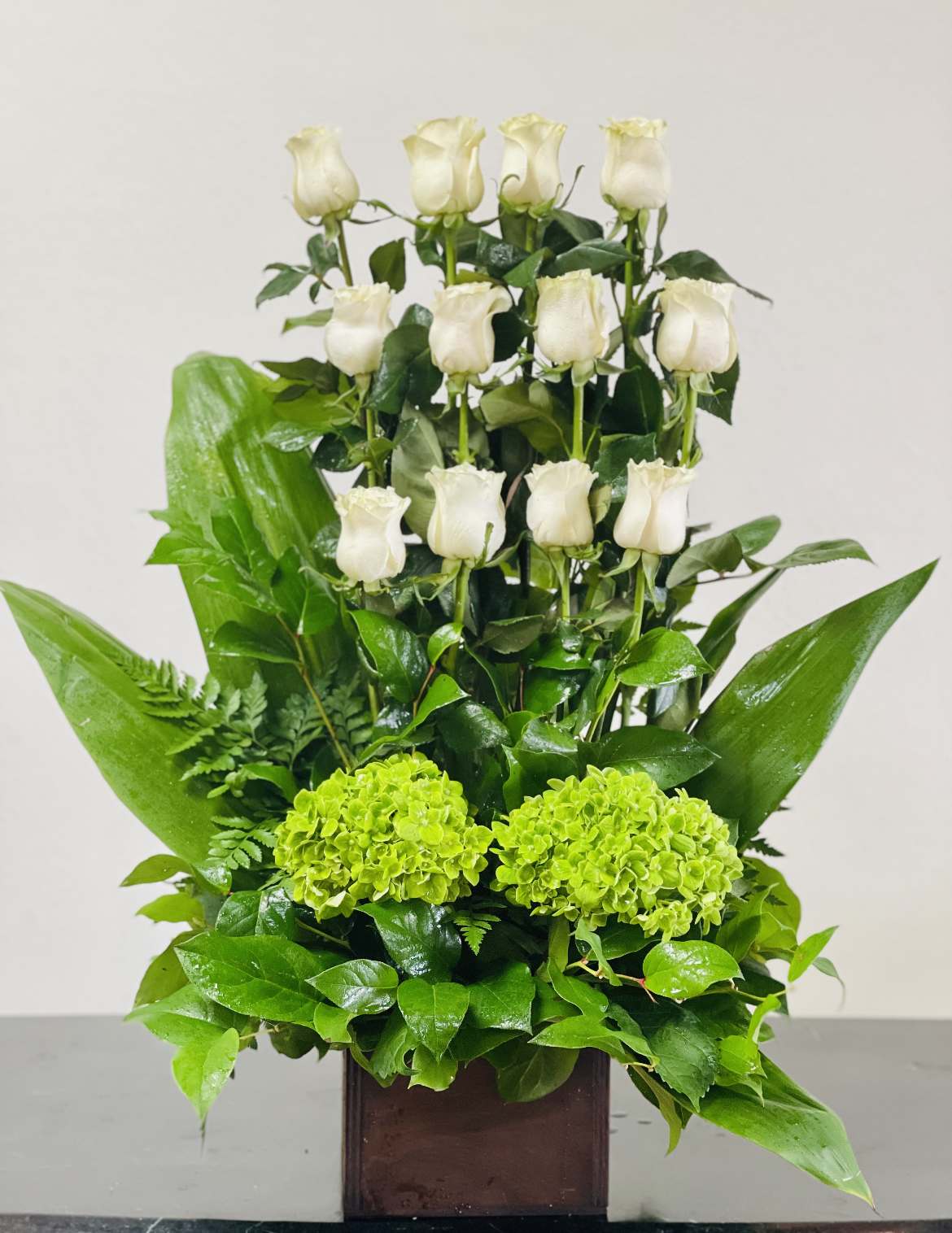 White roses and green hydrangeas in a square vase