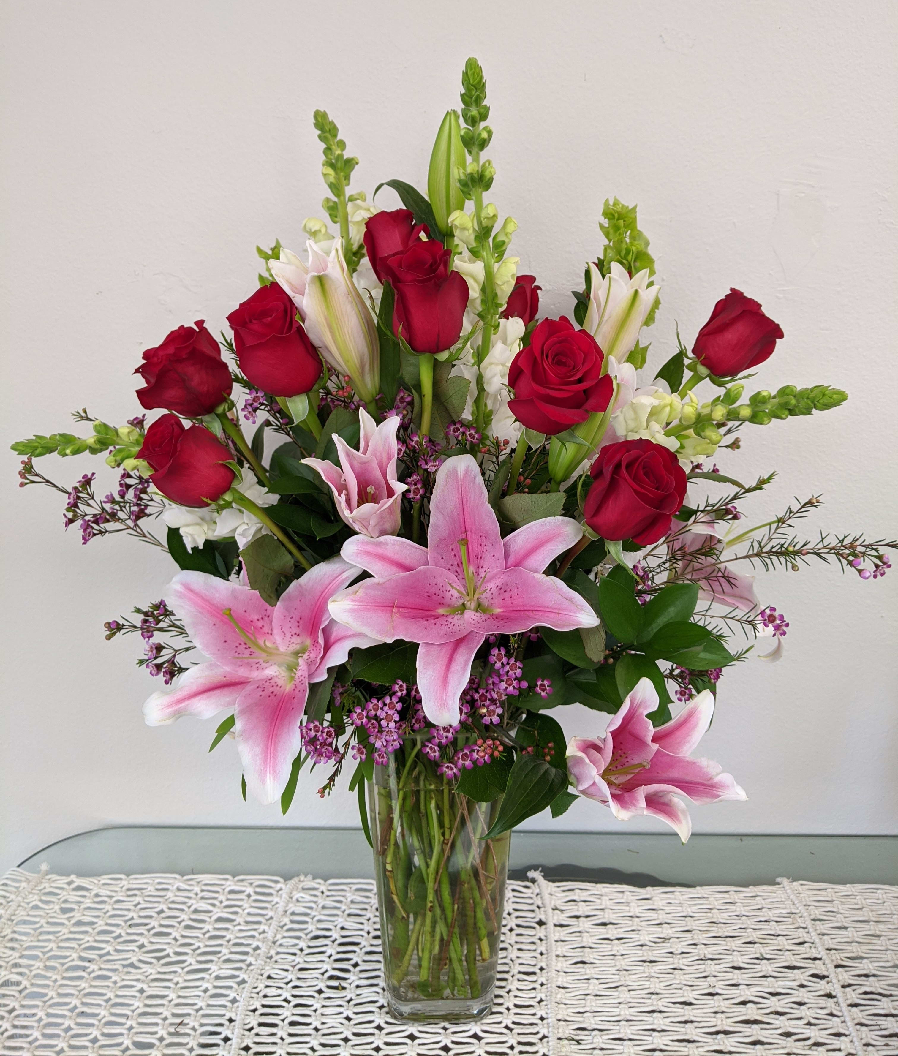 Bouquet of pink lilies and red roses in a clear glass vase