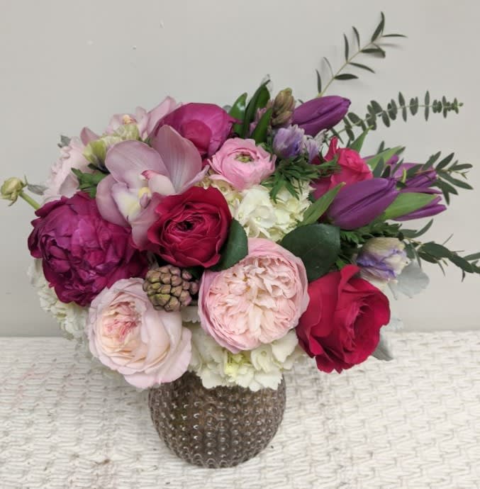 Bouquet of pink, purple, and red flowers in a textured vase