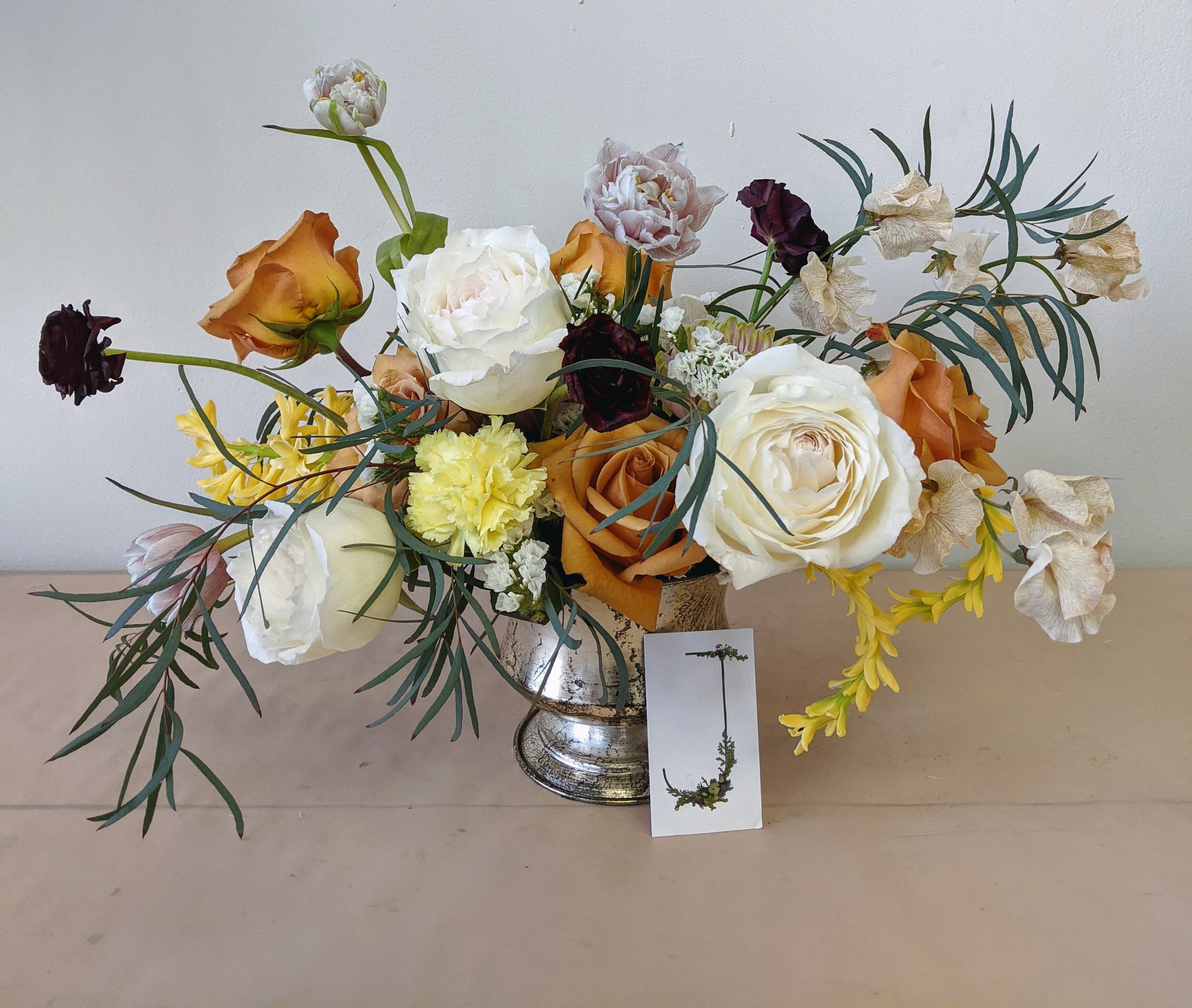 Mixed bouquet of roses, peonies, and carnations in a silver vase