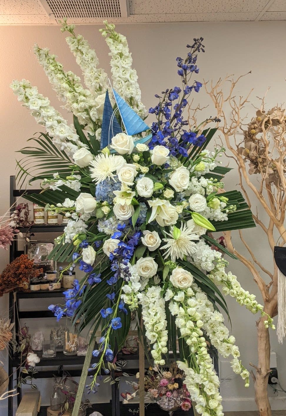 Large standing floral arrangement with white roses and blue flowers