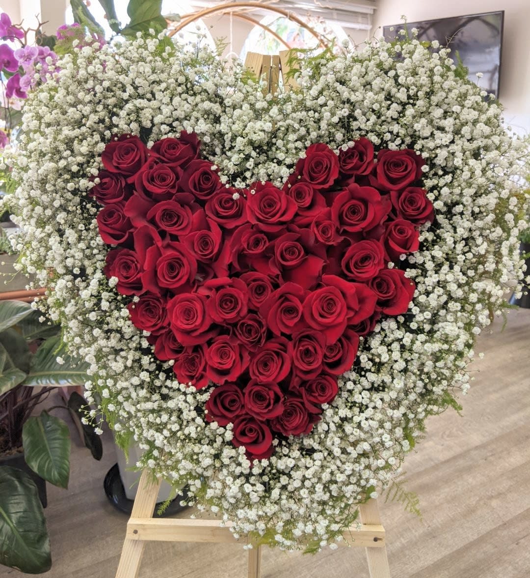 Heart-shaped red rose arrangement surrounded by white baby's breath