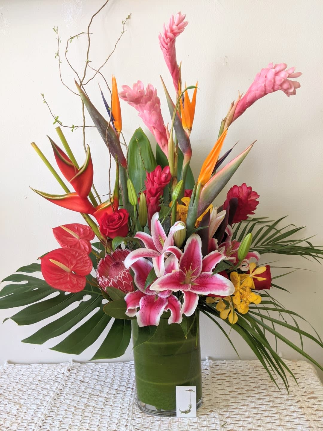 Tropical bouquet with pink lilies and red anthuriums in a glass vase