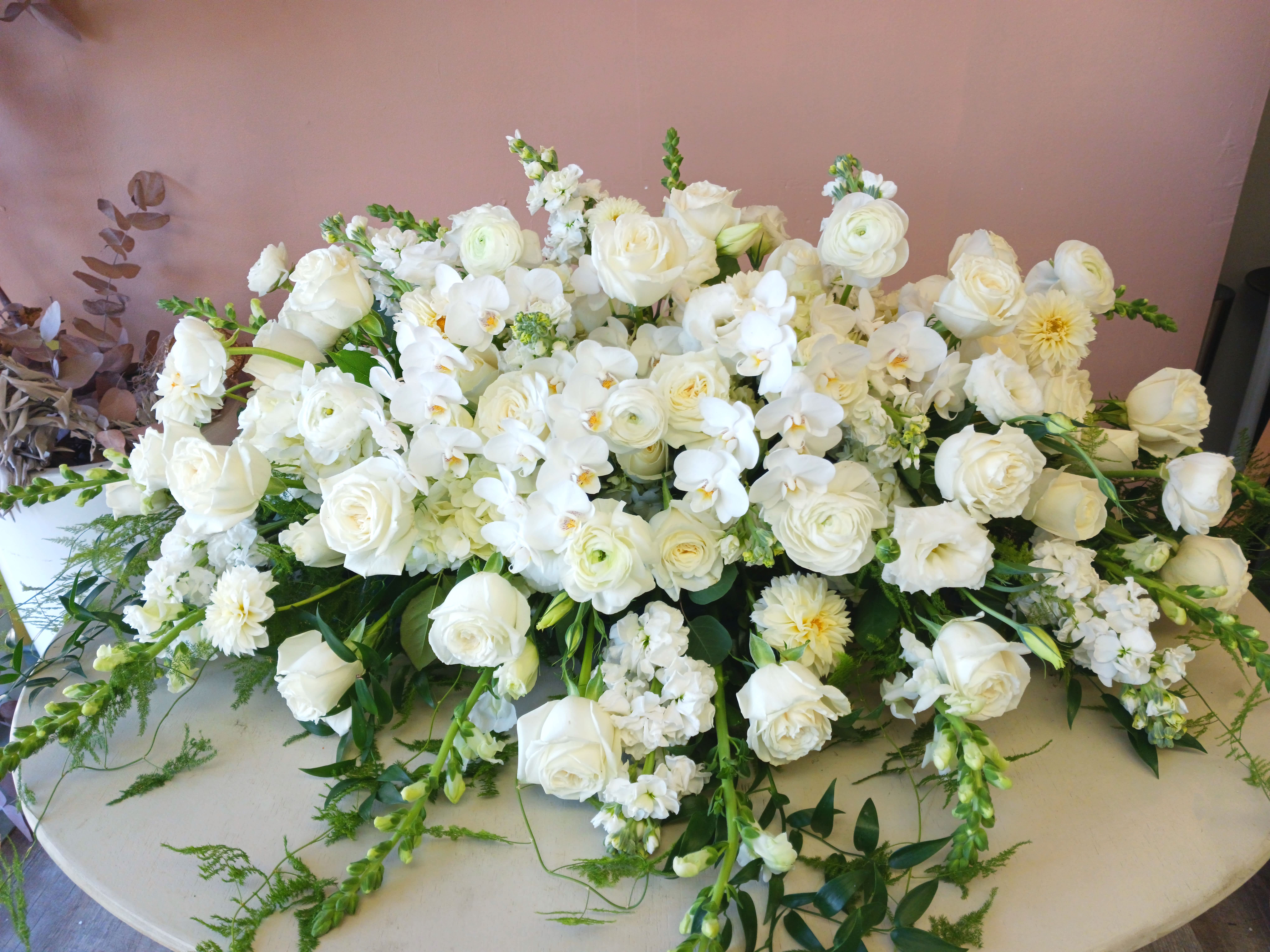 Large white floral arrangement with roses and orchids on a table
