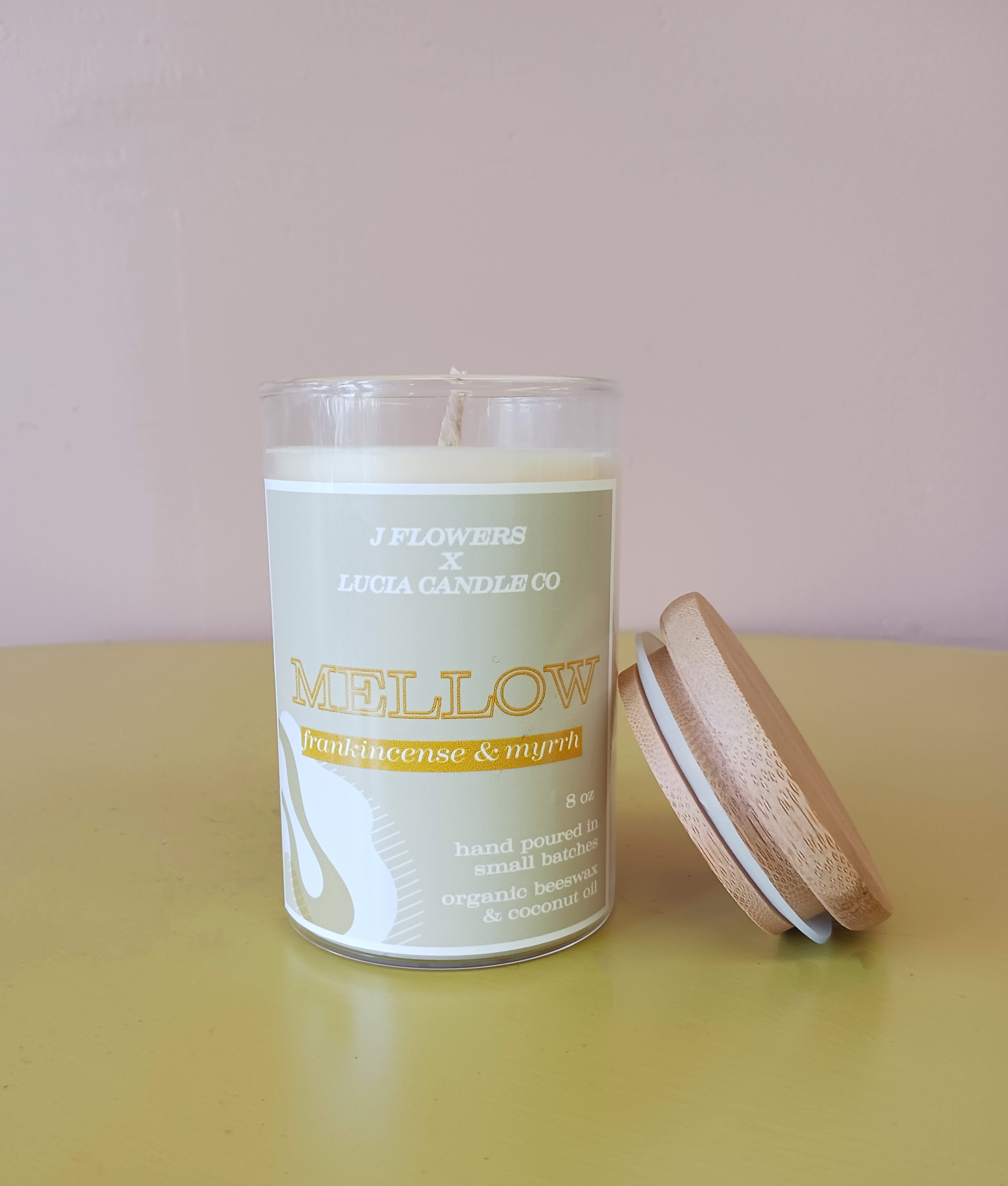 A scented candle in a glass jar with a wooden lid beside it