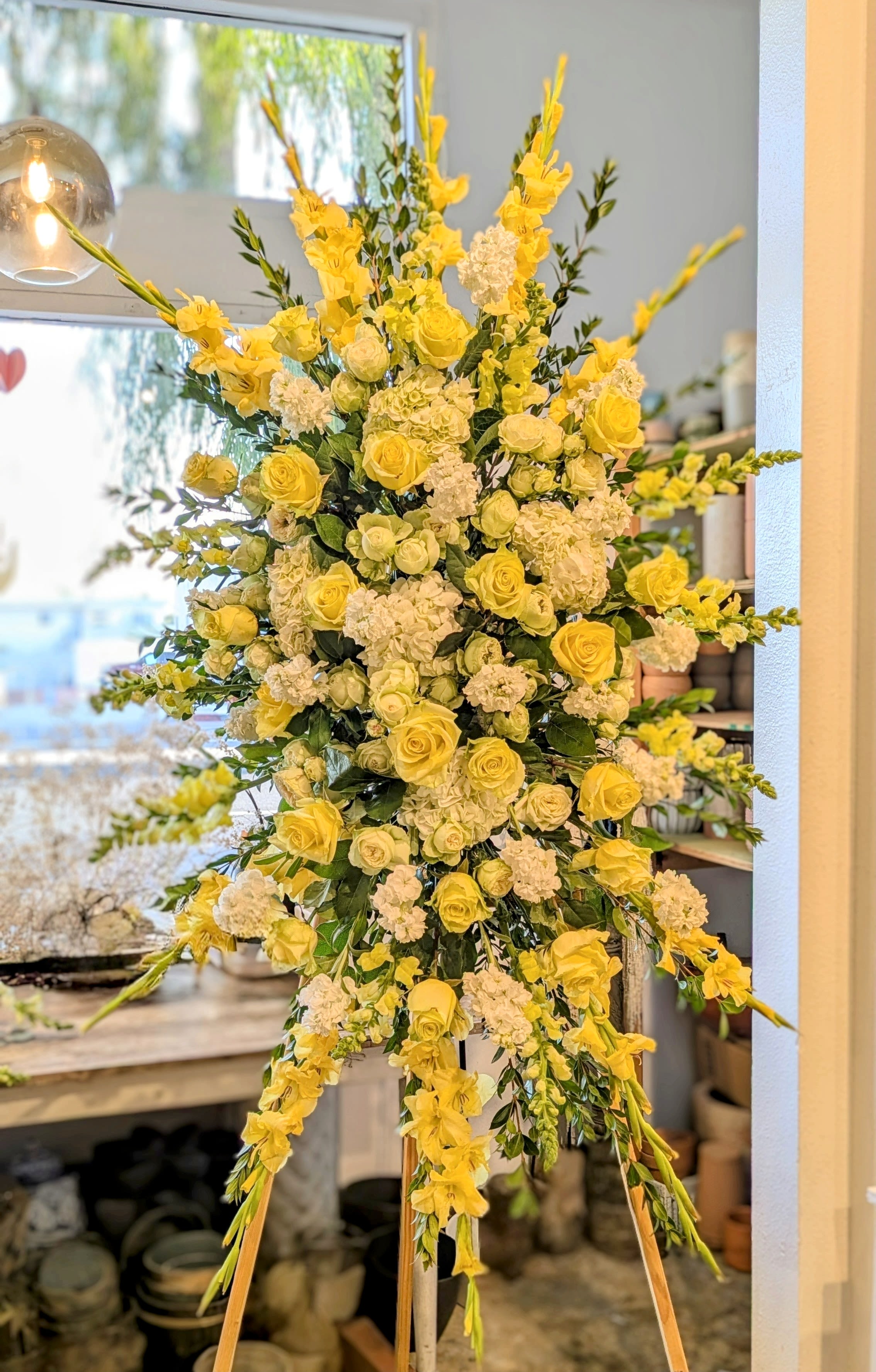 Tall yellow and white floral standing arrangement on an easel
