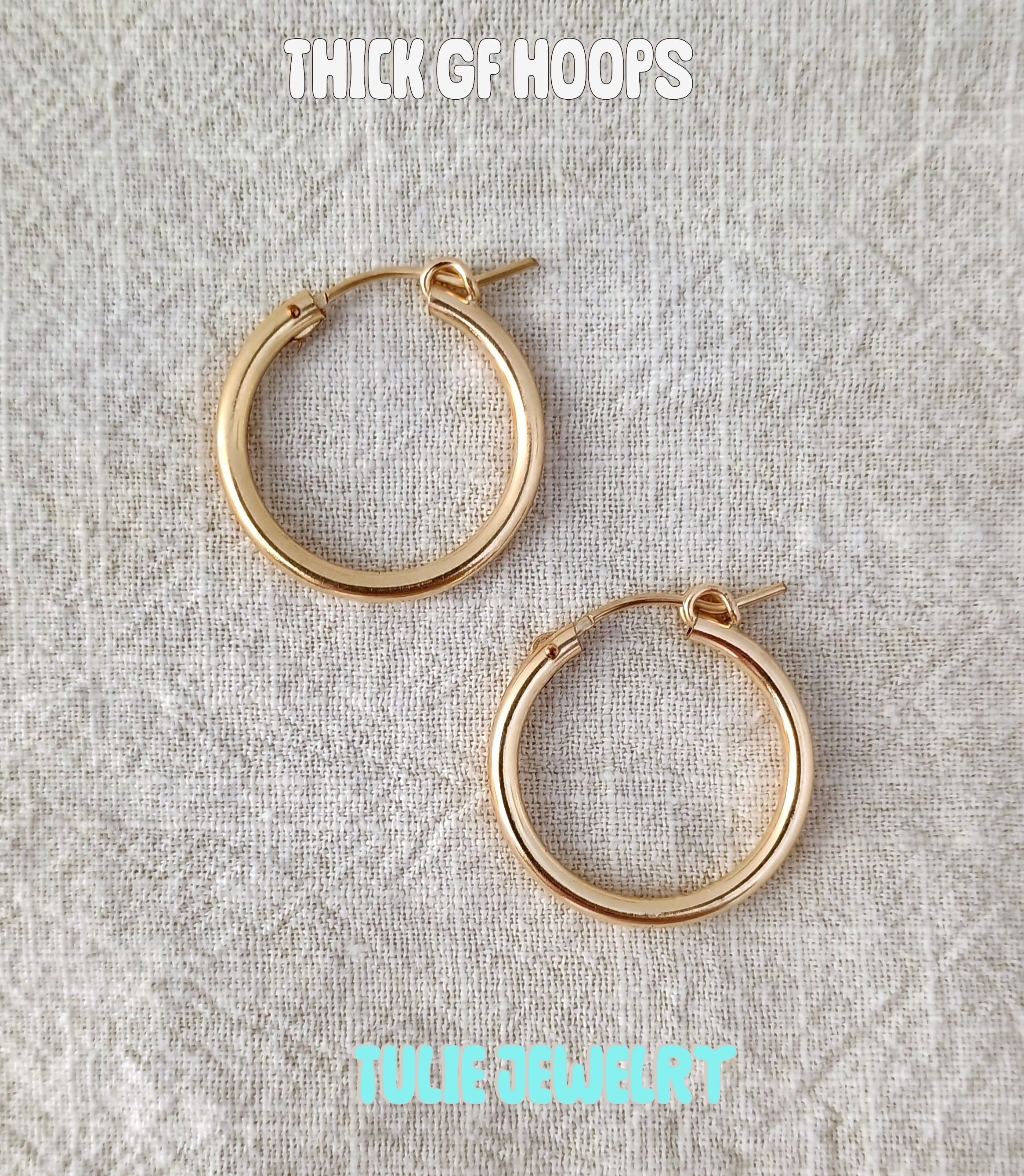 Pair of gold hoop earrings on a textured fabric background