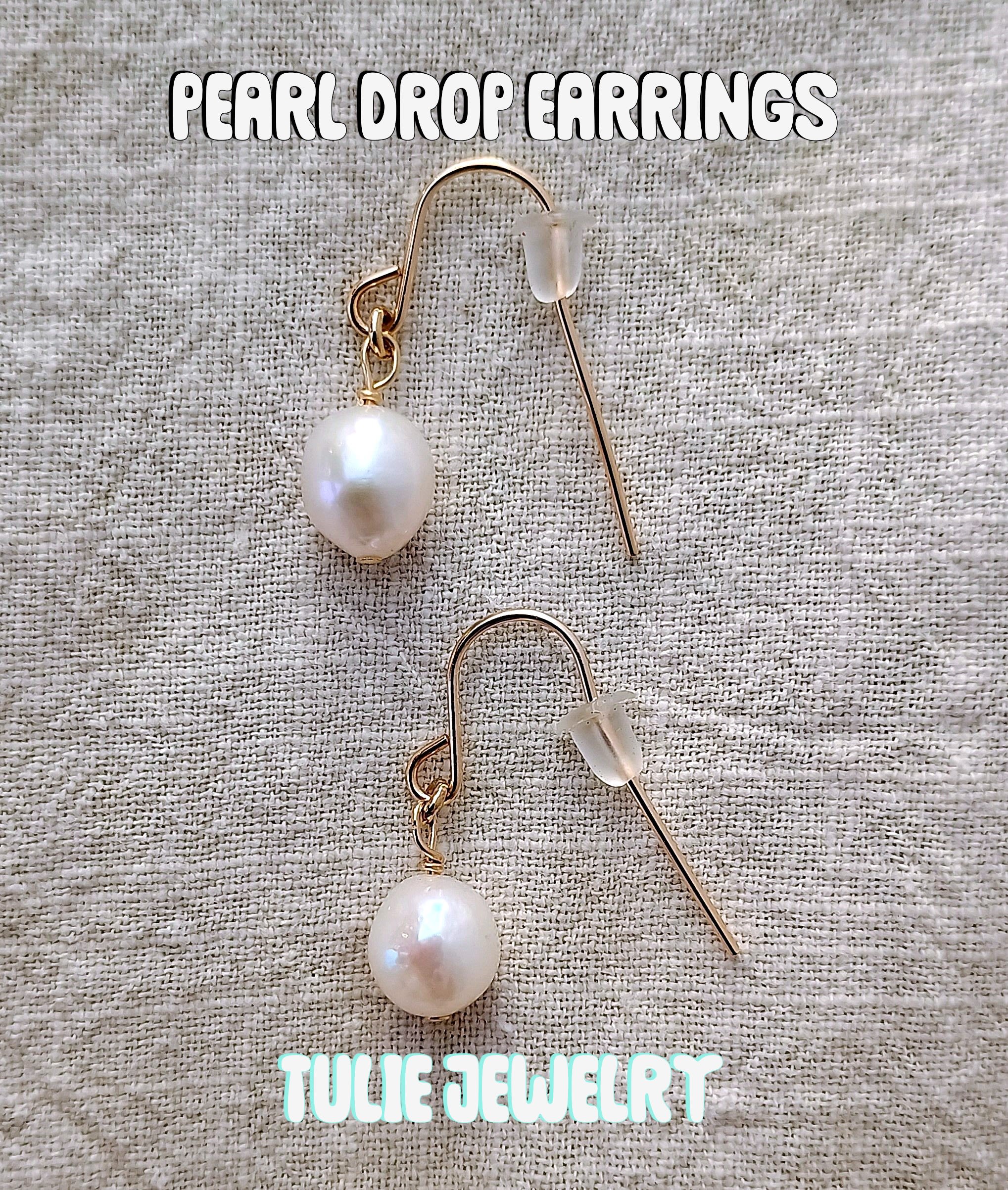 Pair of pearl drop earrings on a textured fabric background