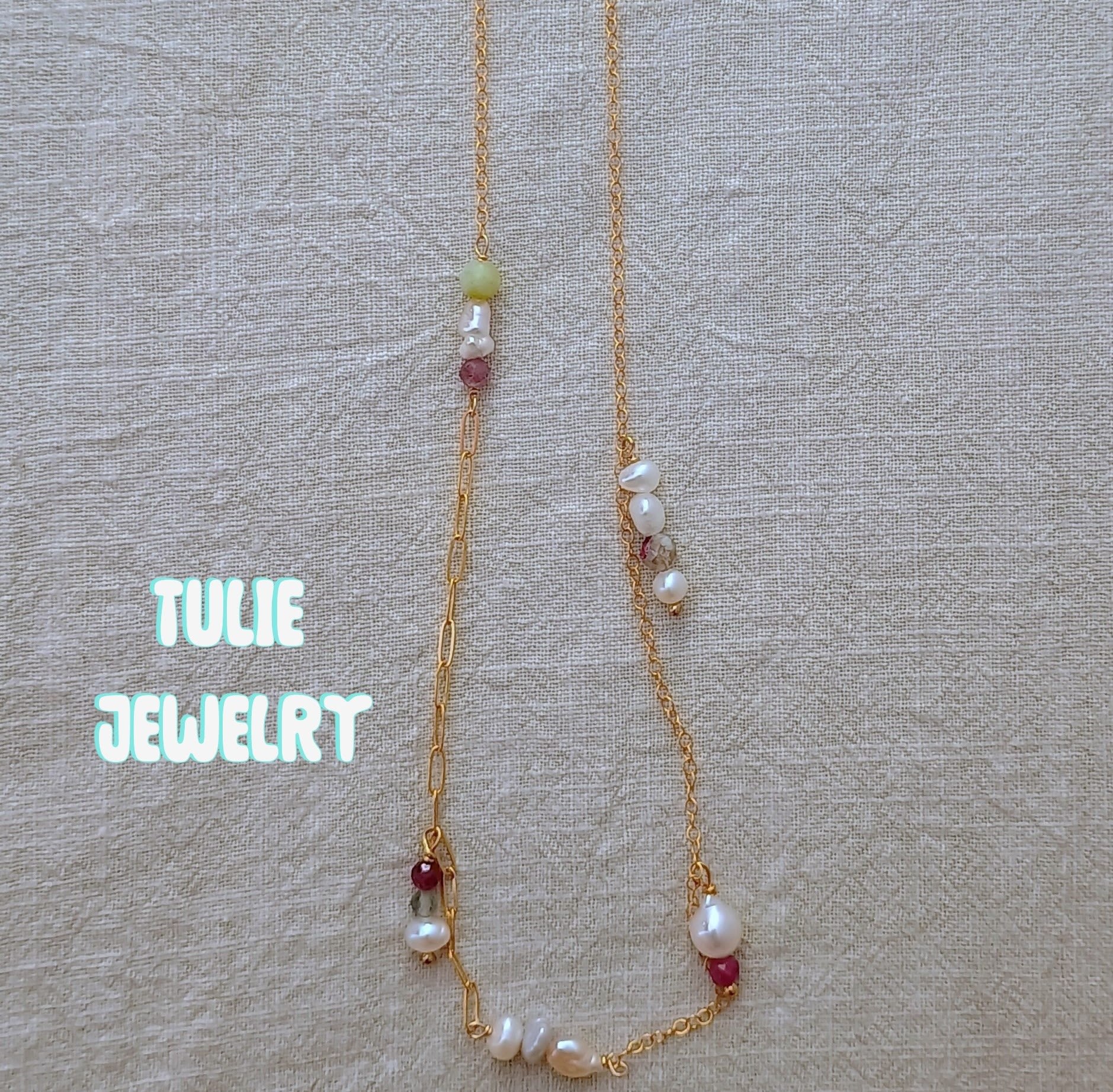 Gold necklace with pearl and bead accents on beige fabric