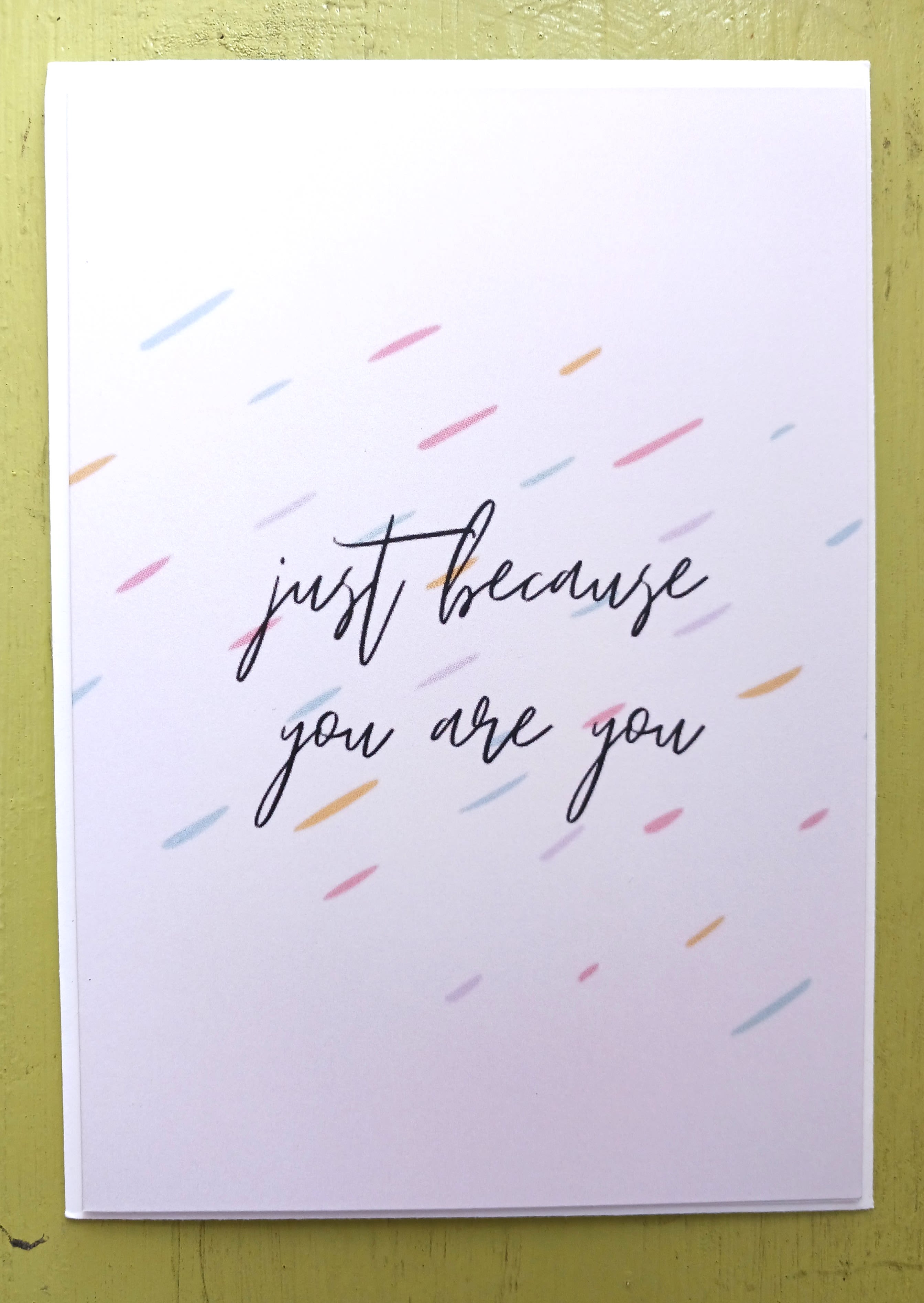 White greeting card with 'just because you are you' text and scattered pastel dashes.