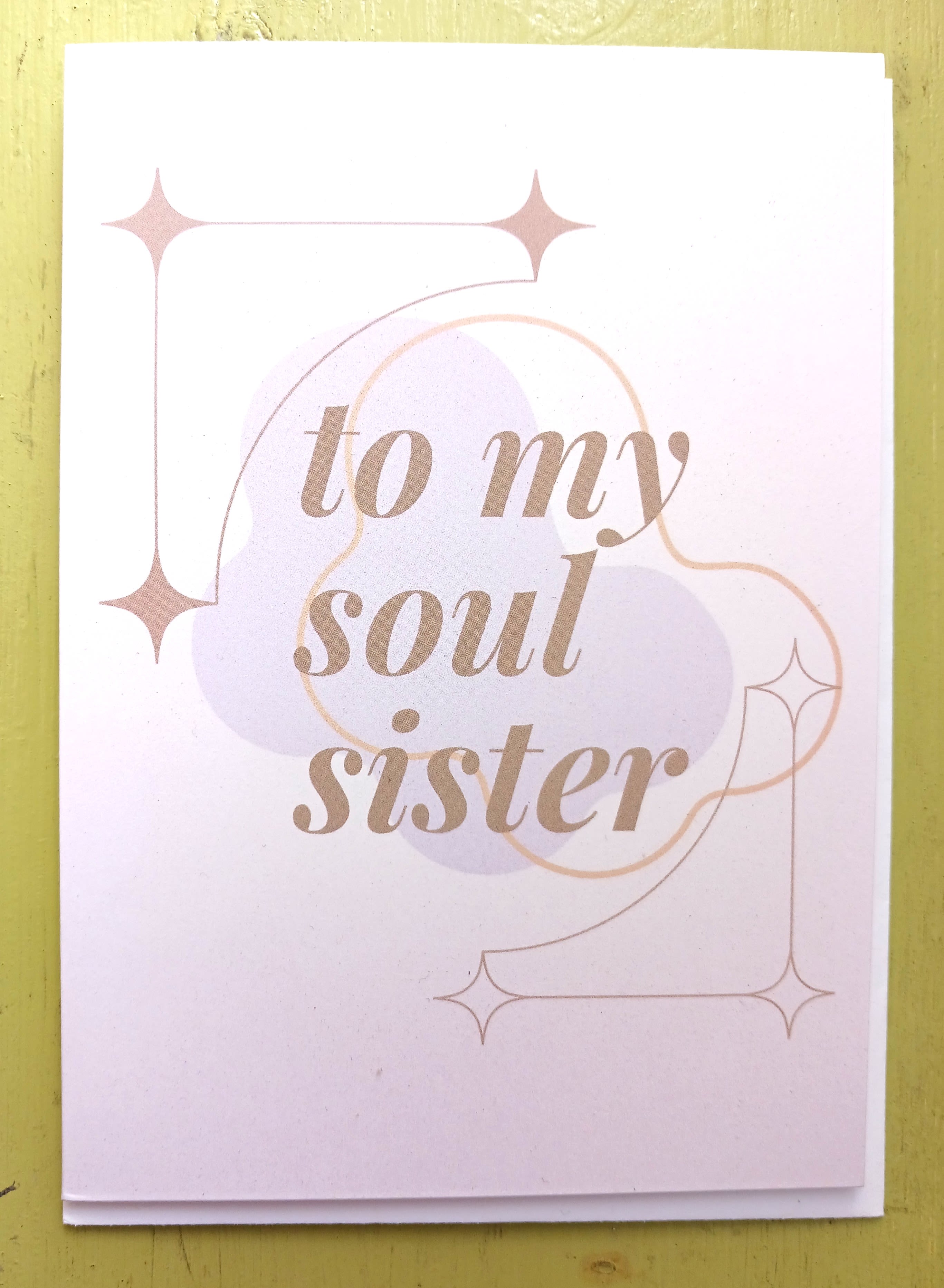 Greeting card reading 'to my soul sister' in tan script with pastel shapes and star accents.