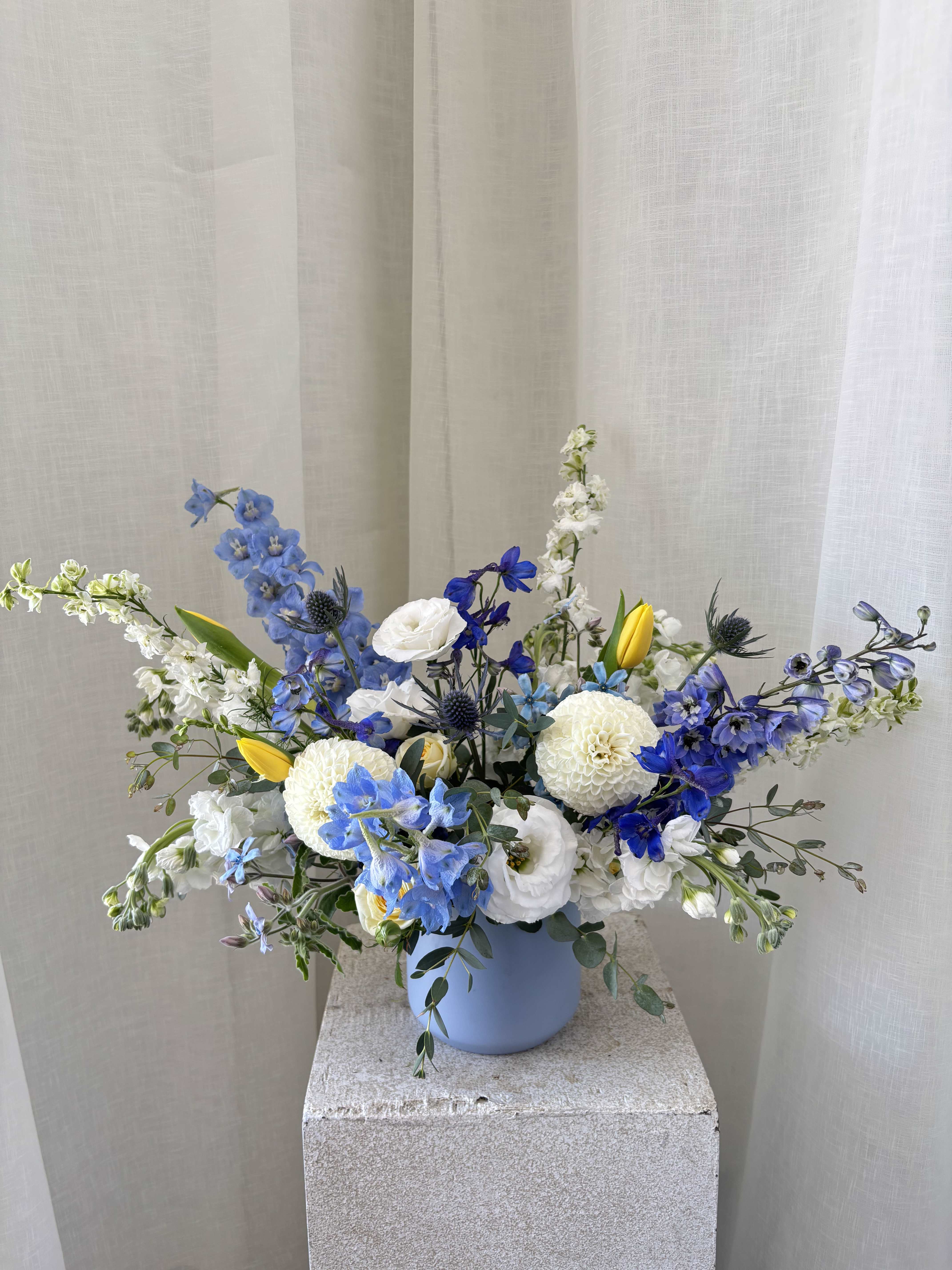 Blue and white floral arrangement in a light blue vase