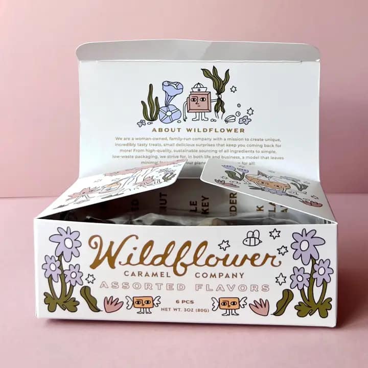 Open box of assorted caramels with floral illustrations on the packaging
