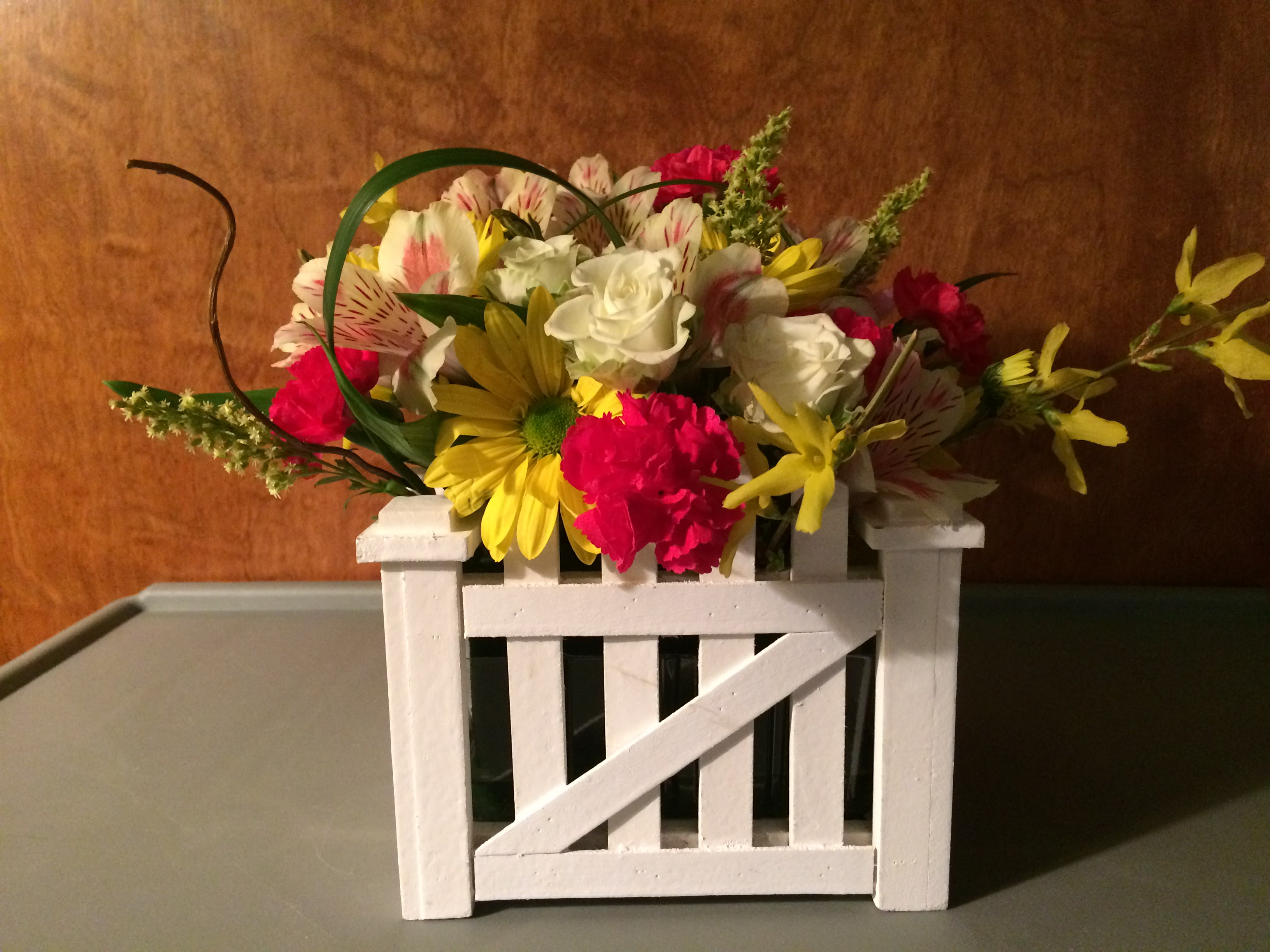 Mixed bouquet in a white wooden crate with yellow, white, and pink flowers