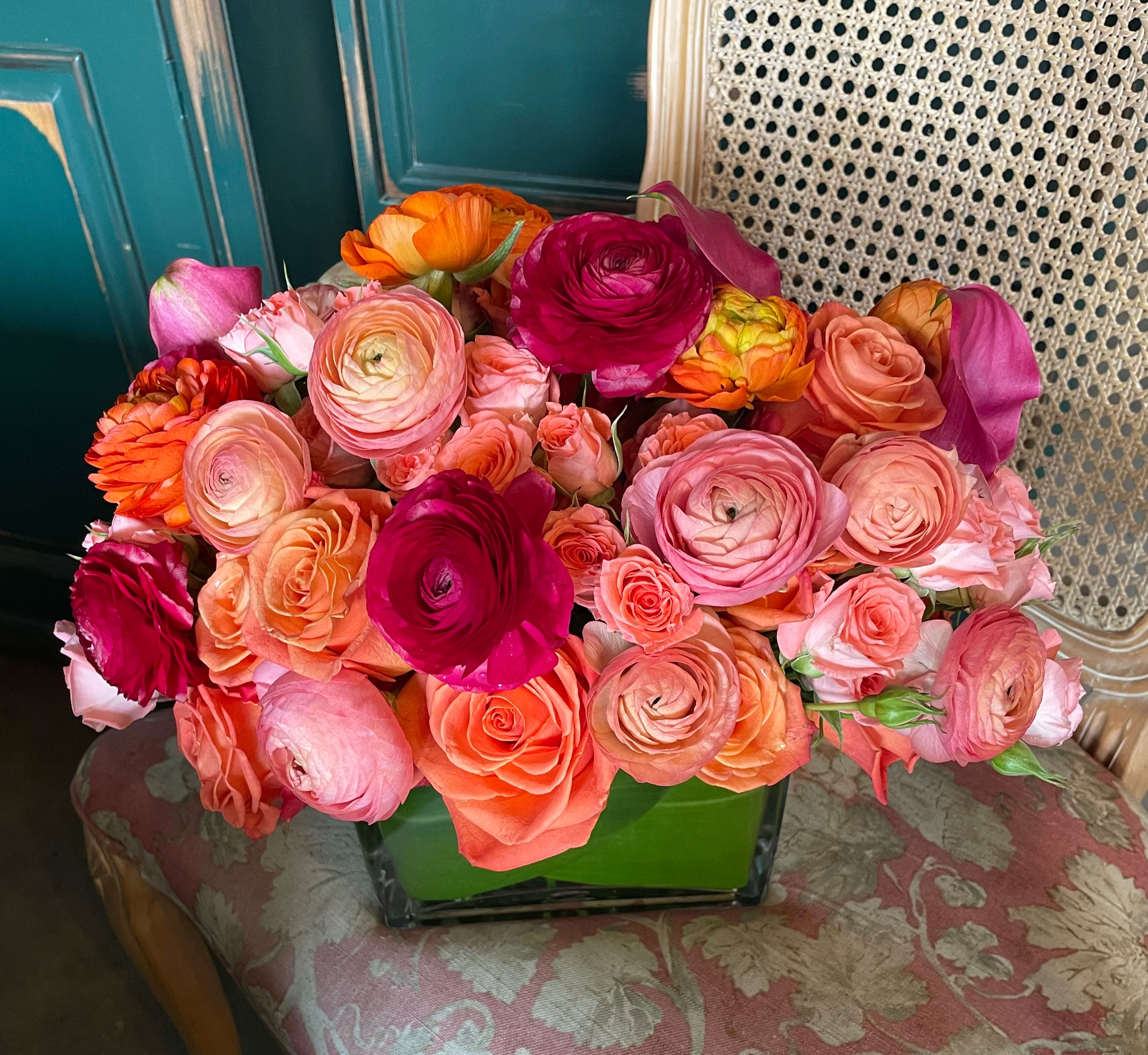 Mixed bouquet of pink, coral, orange, and magenta flowers in a green vase