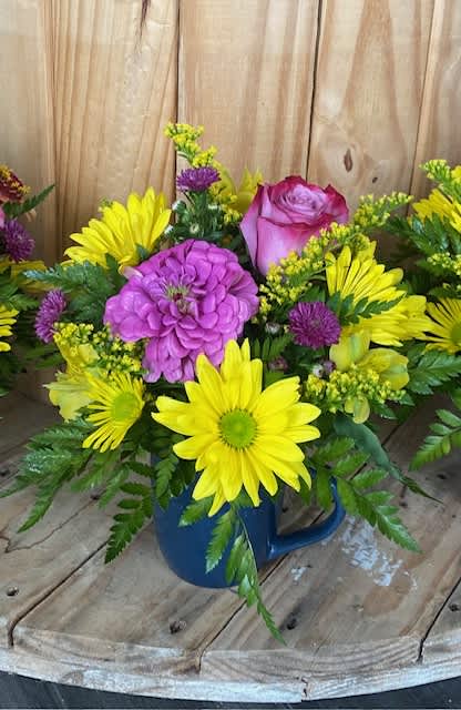 Bright mixed bouquet in a blue mug with yellow daisies and pink roses