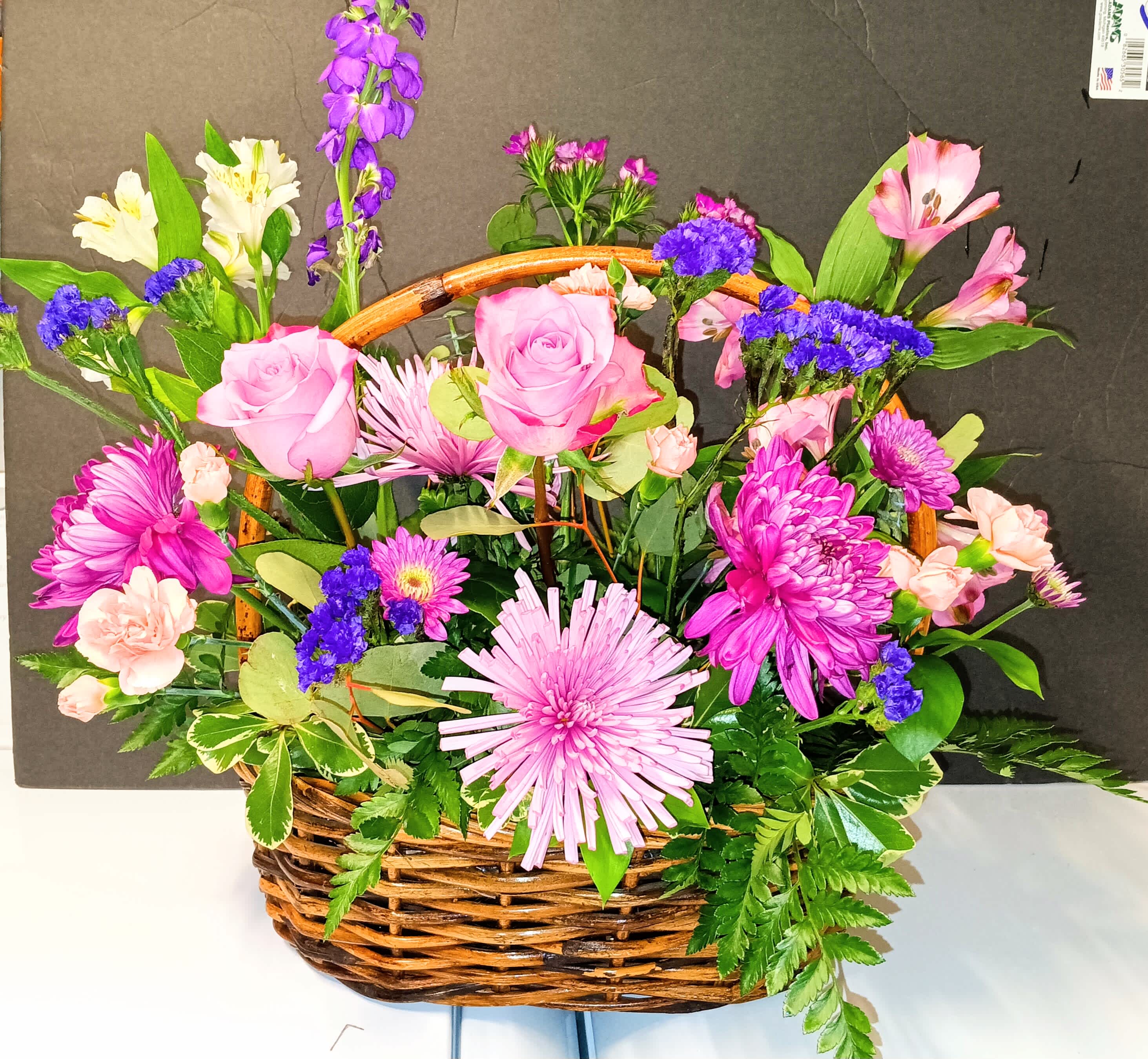 Basket arrangement of pink roses, chrysanthemums, and mixed blooms